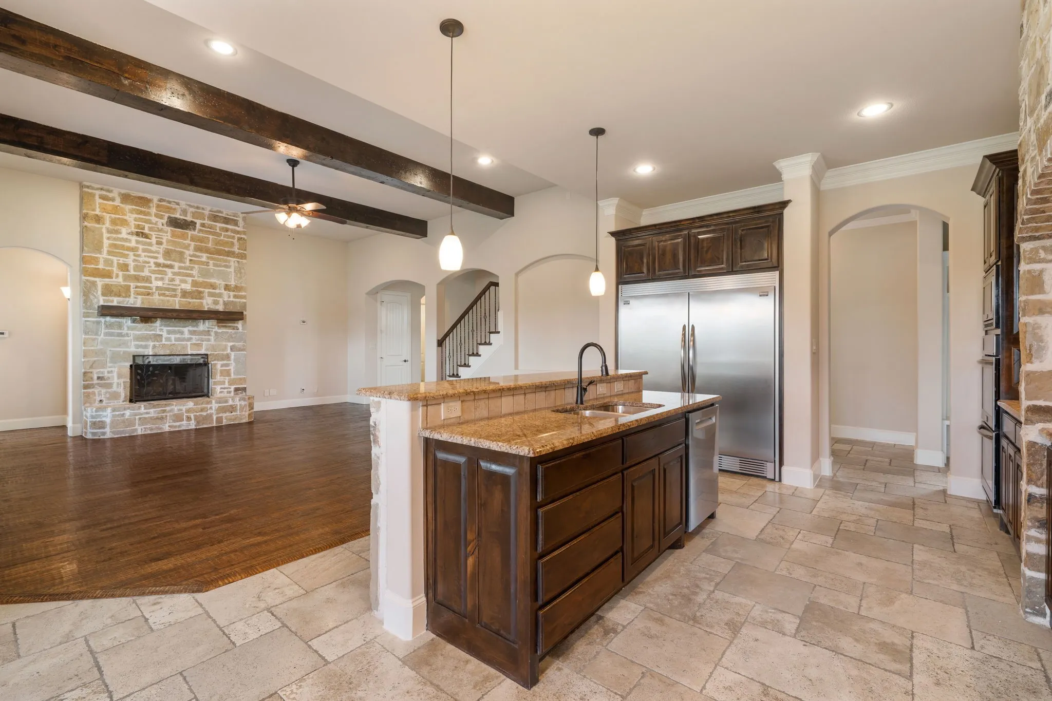 Spacious interior with exposed wood beams, stone-faced fireplace, and wood-finish flooring