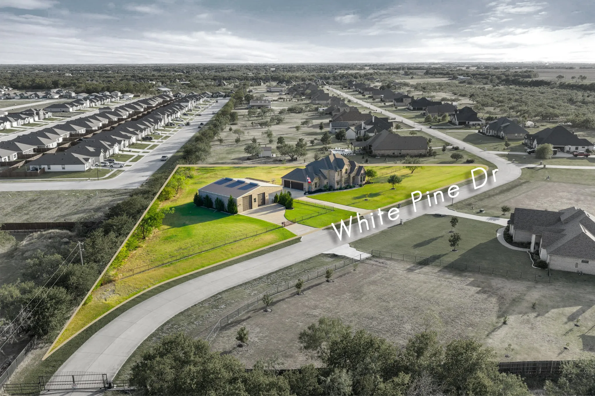 Expansive corner lot with a single-story residence and detached garage, featuring a paved driveway and green lawn areas
