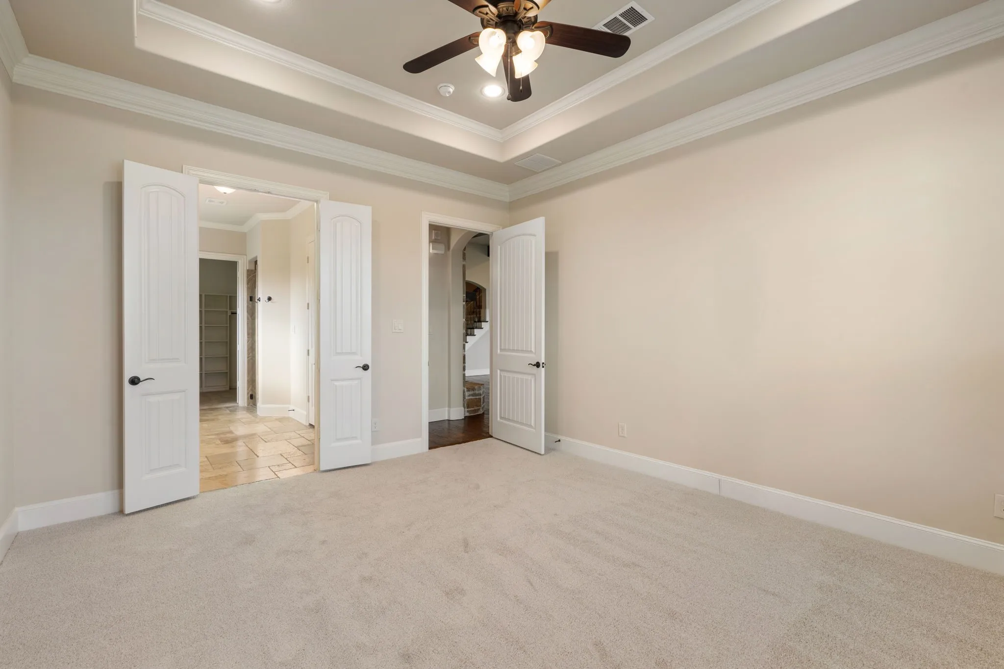 Recessed lighting, ceiling fan, tray ceiling, crown molding, and light-colored carpeting