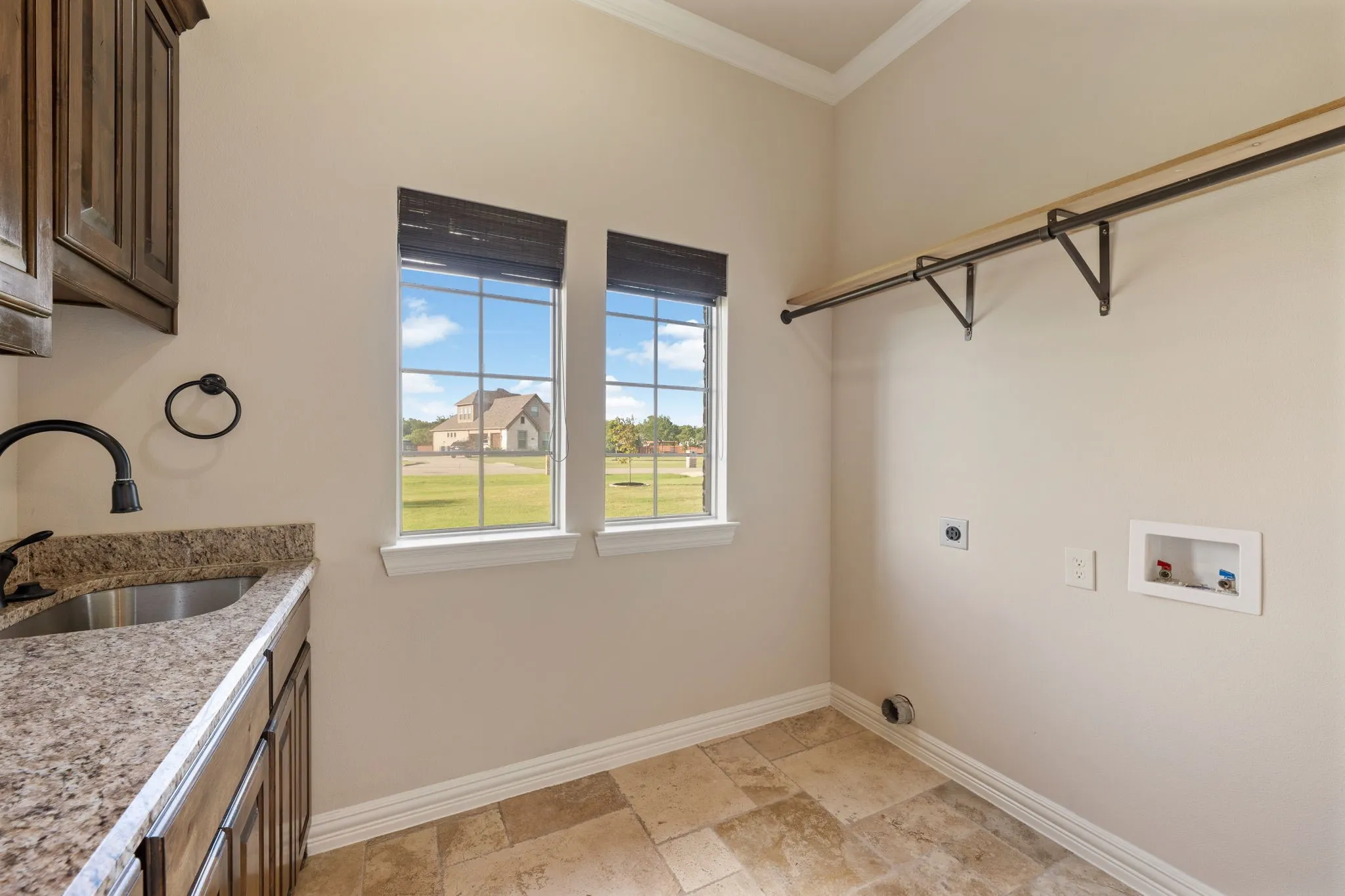 Laundry room featuring a utility sink with a gooseneck faucet, light-colored granite-style countertop, and built-in wood cabinetry