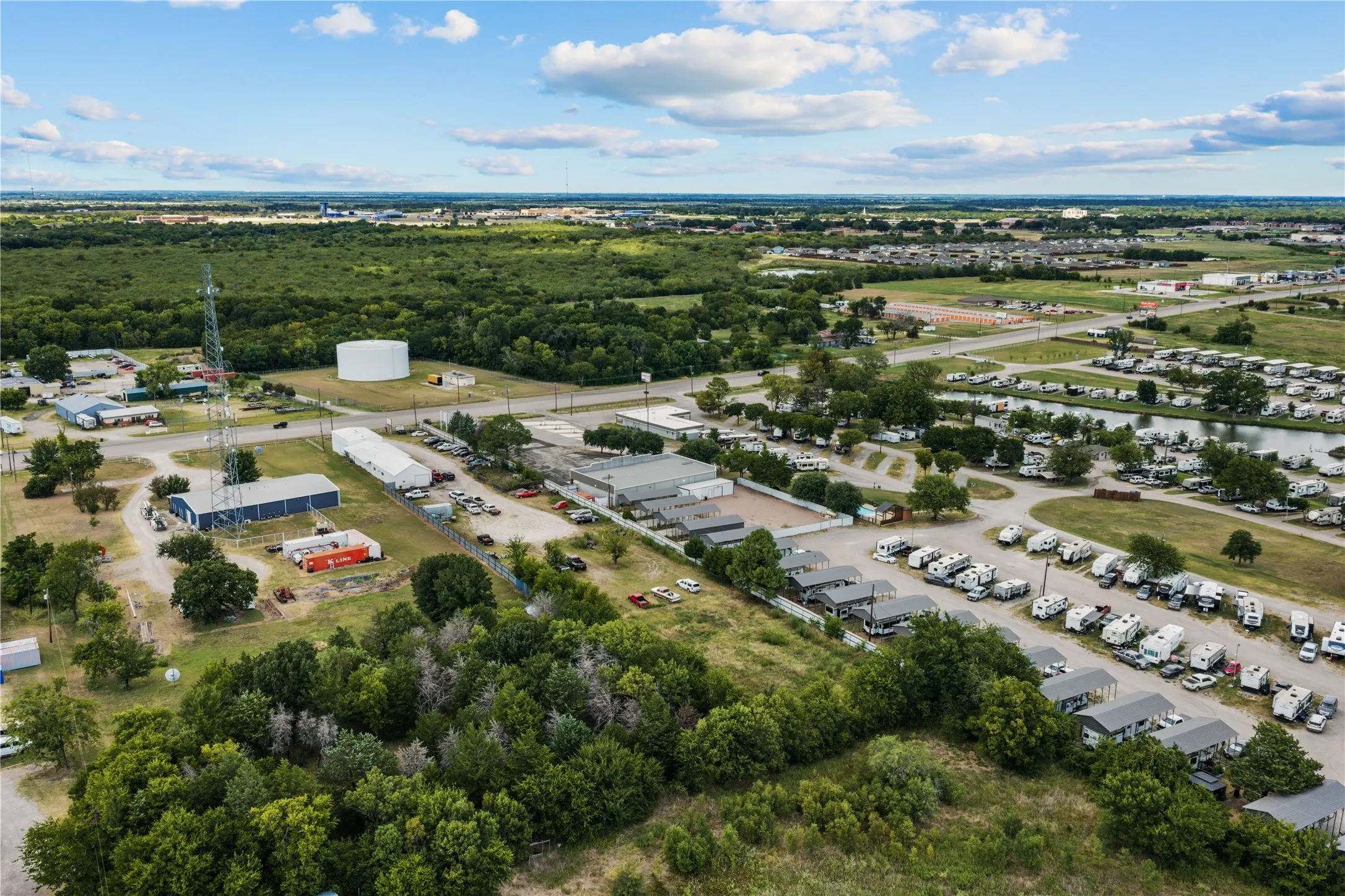 Expansive aerial perspective showcasing a commercial property with multiple buildings, a water tower, and large paved areas