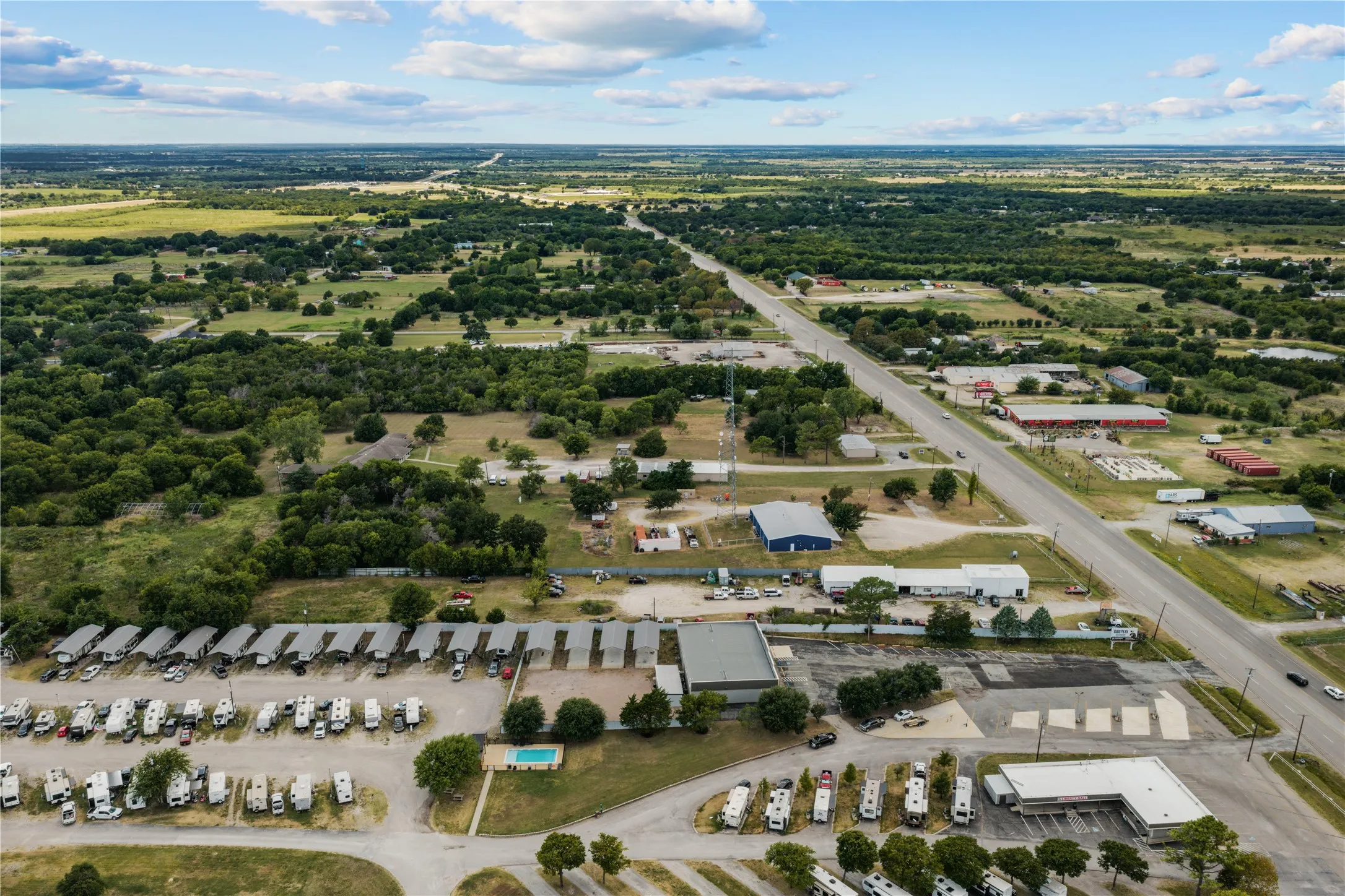 Expansive property featuring multiple commercial buildings, paved parking areas, and abundant green space