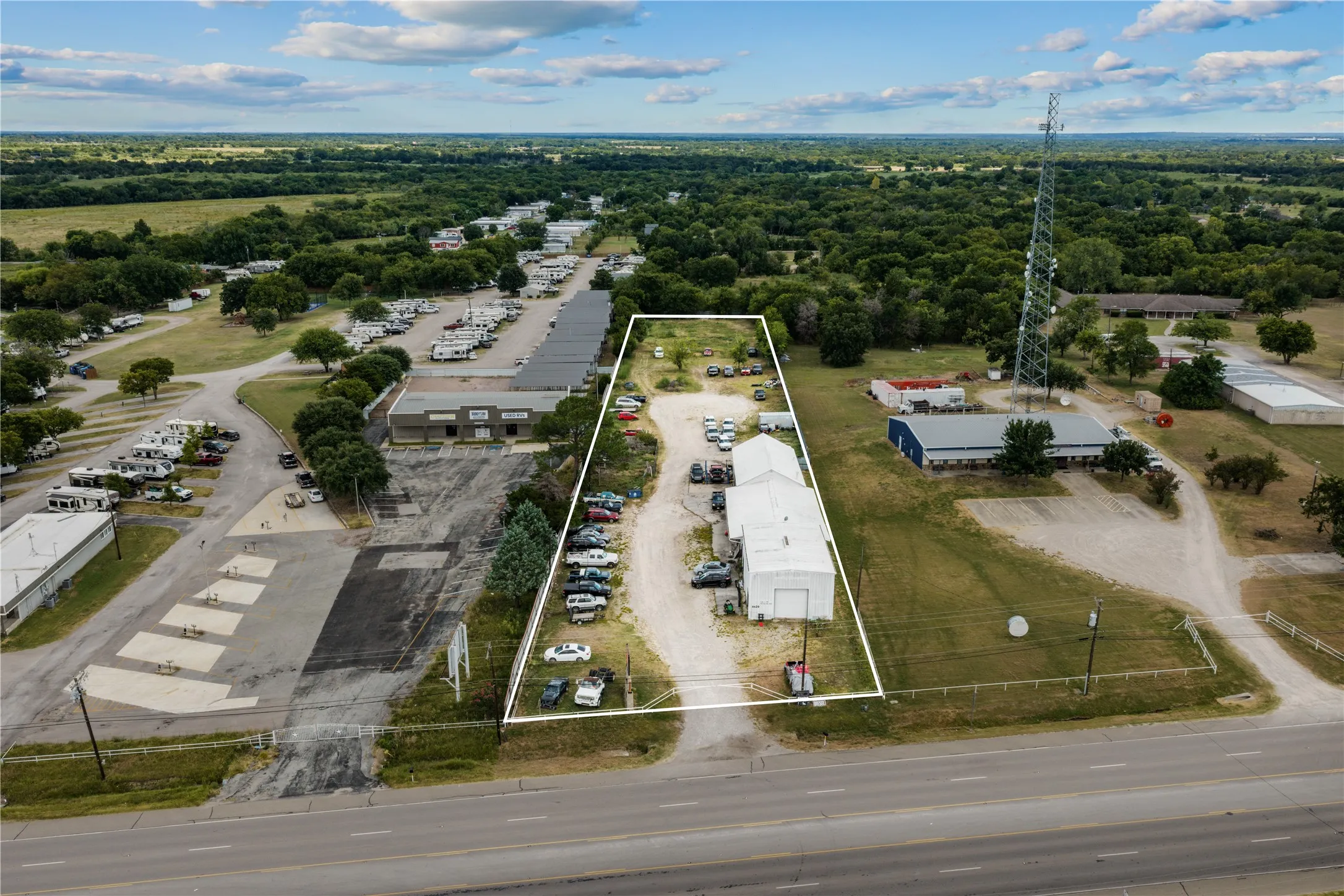 Commercial property featuring two large warehouse-style buildings, extensive gravel parking, and direct road frontage