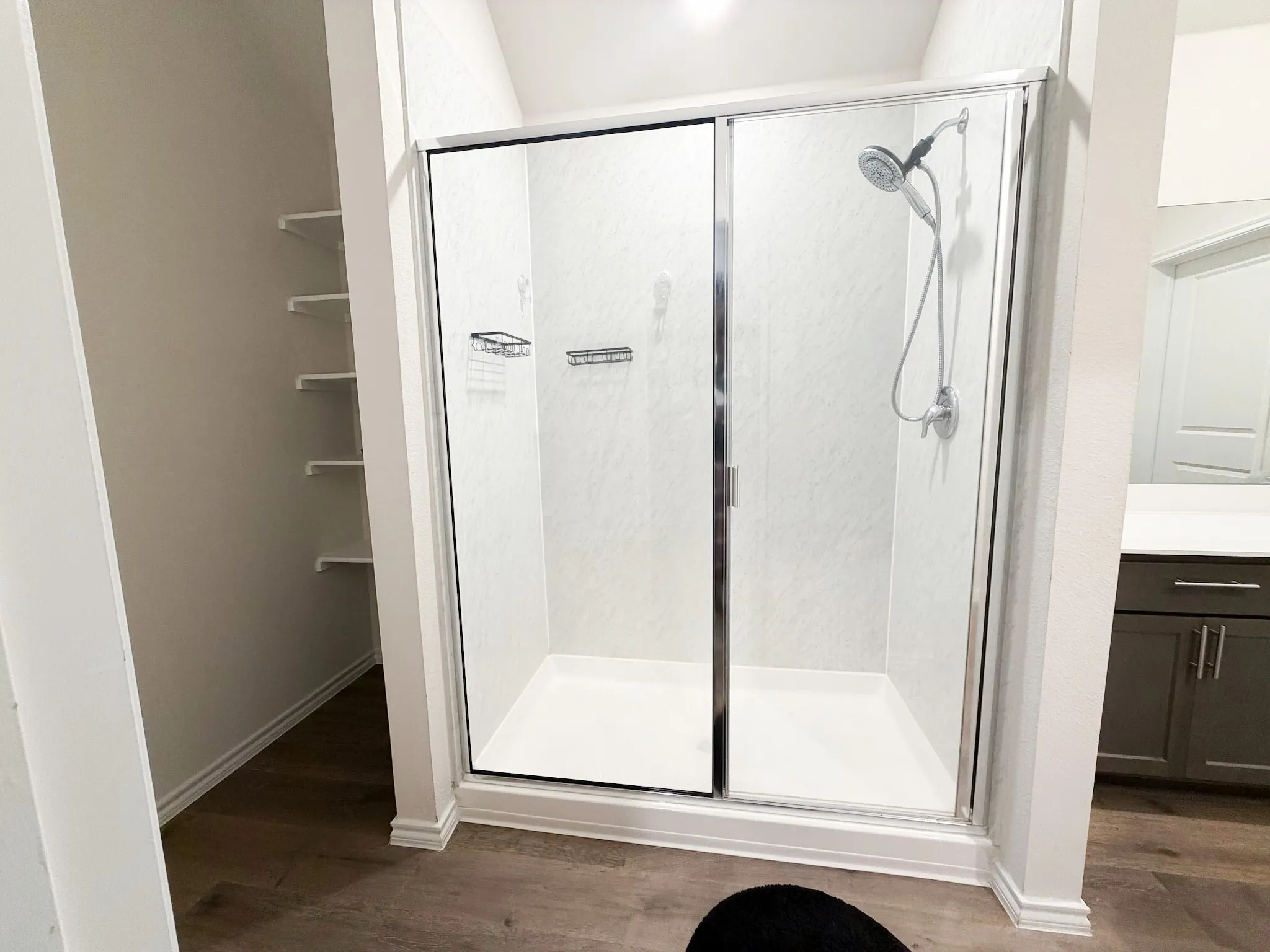 Modern frameless glass shower enclosure with dual sliding doors, chrome hardware, and integrated showerhead with handheld spray