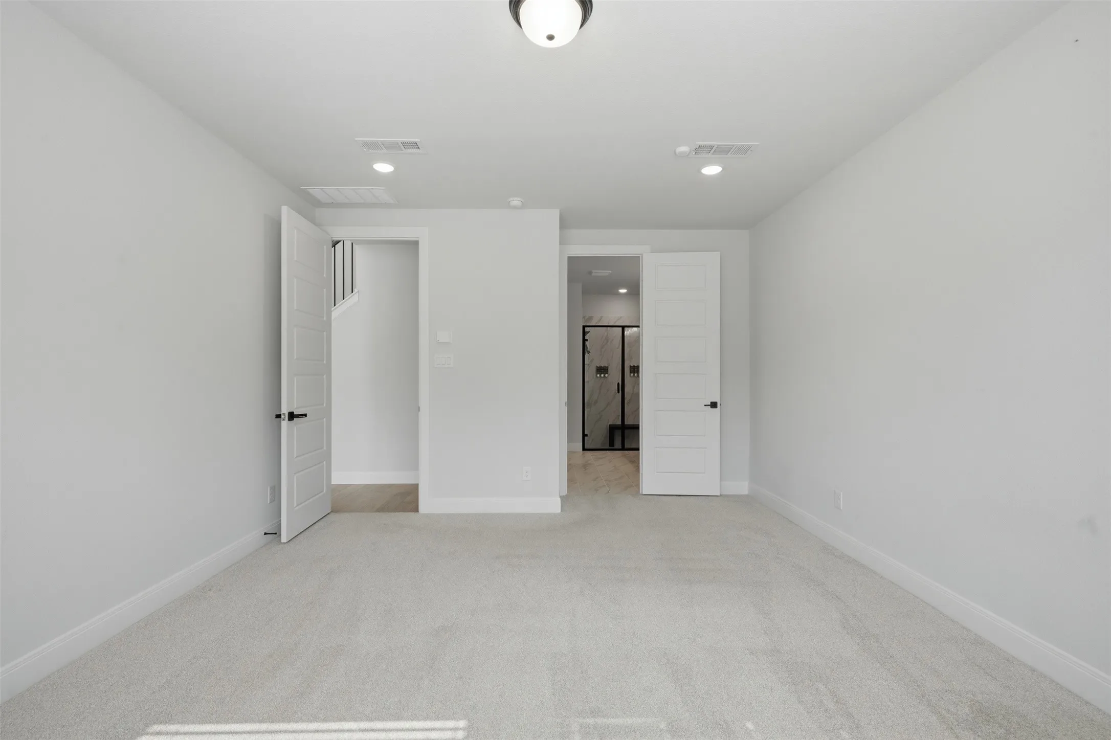 Inviting interior featuring plush carpeting, recessed lighting, and a sleek modern flush-mount fixture, creating a comfortable and polished atmosphere