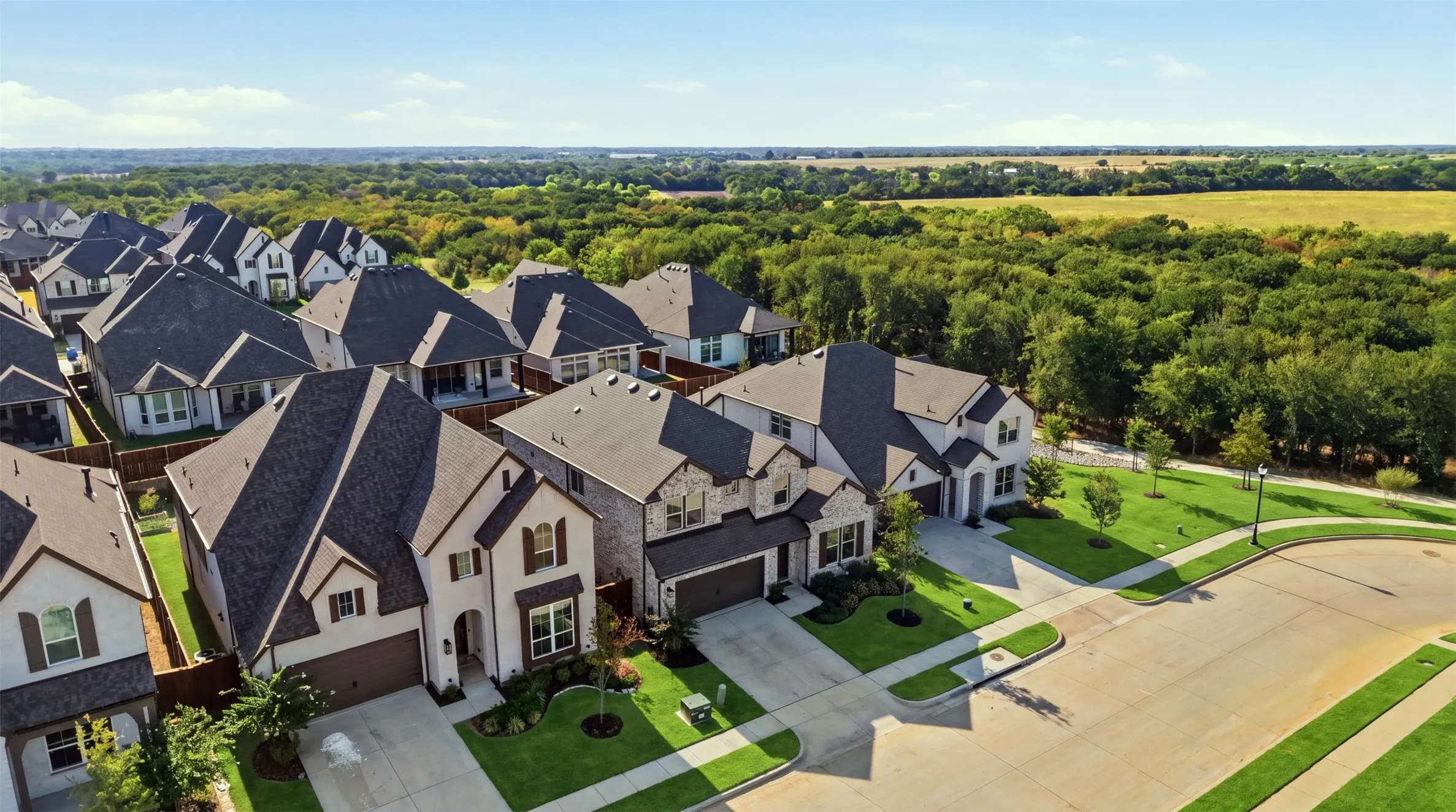 Beautifully presented homes featuring a blend of stone and siding exteriors, dark shingle roofs, attached garages, and manicured landscaping for a polished, modern curb appeal