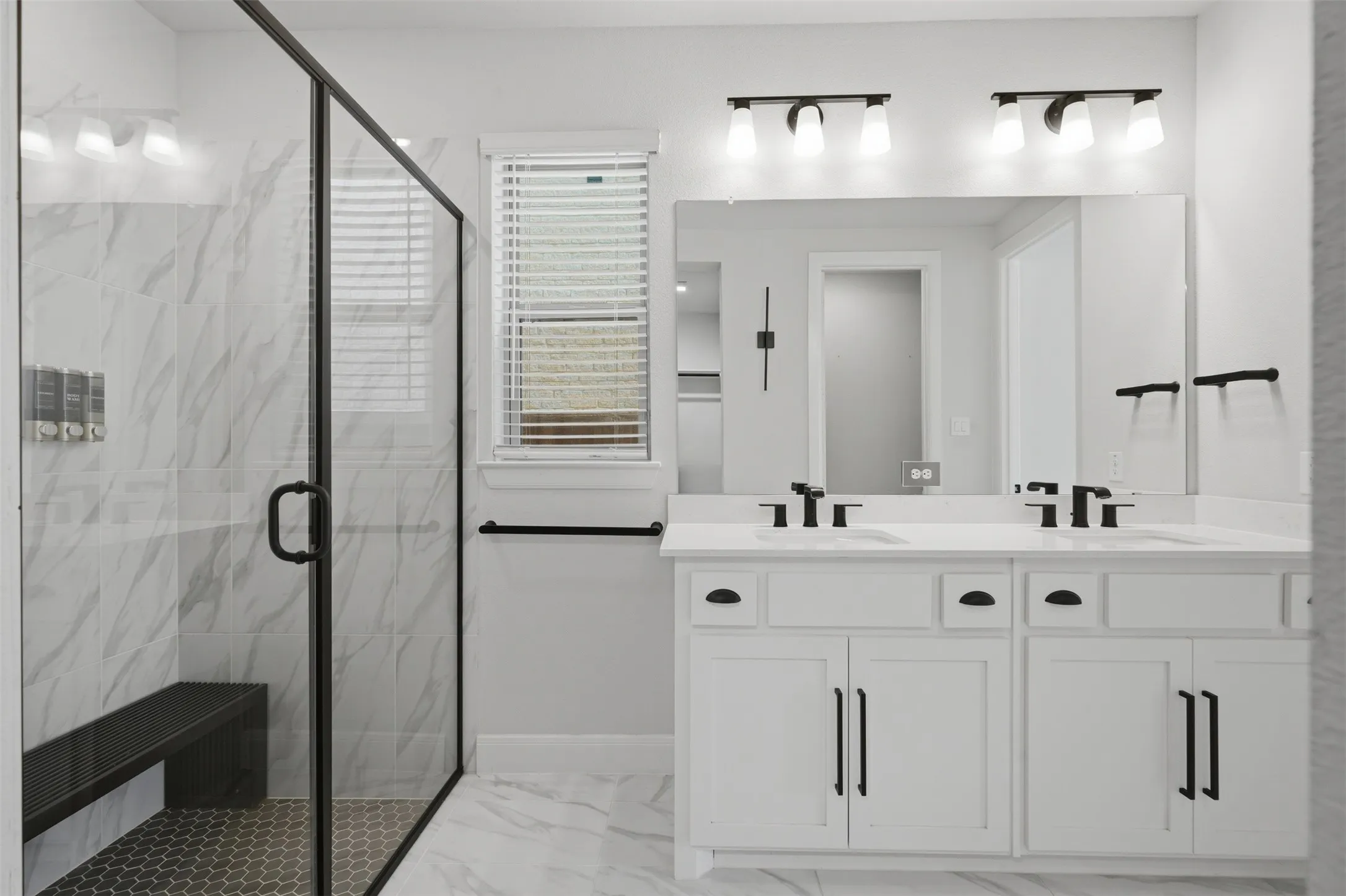 Spacious primary bath featuring a double vanity with white cabinetry and matte black hardware, complemented by a separate walk-in shower with sleek modern finishes