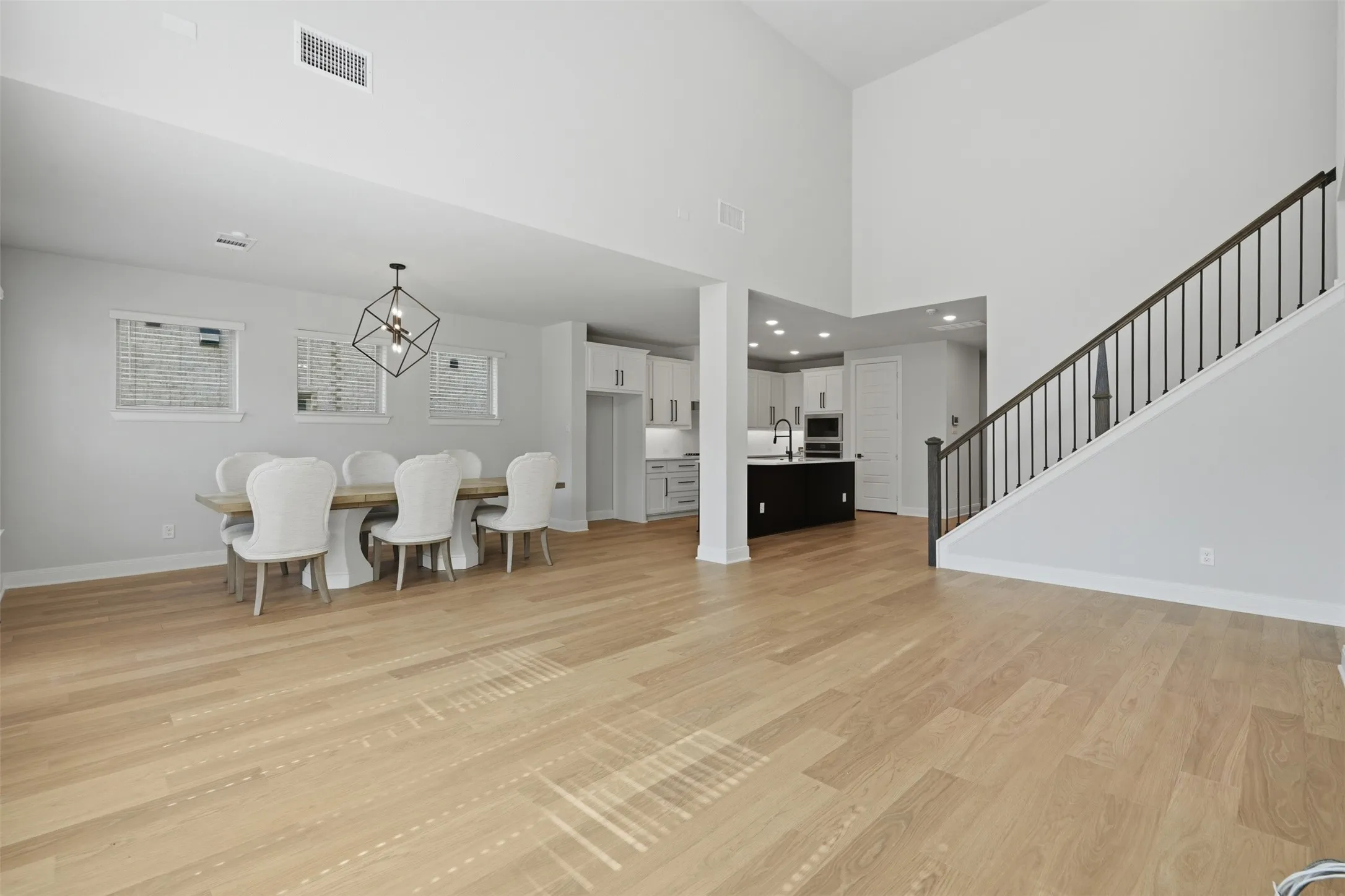 Spacious, open-concept living area featuring abundant natural light, soaring ceilings, and seamless flow between the living, dining, and kitchen spaces