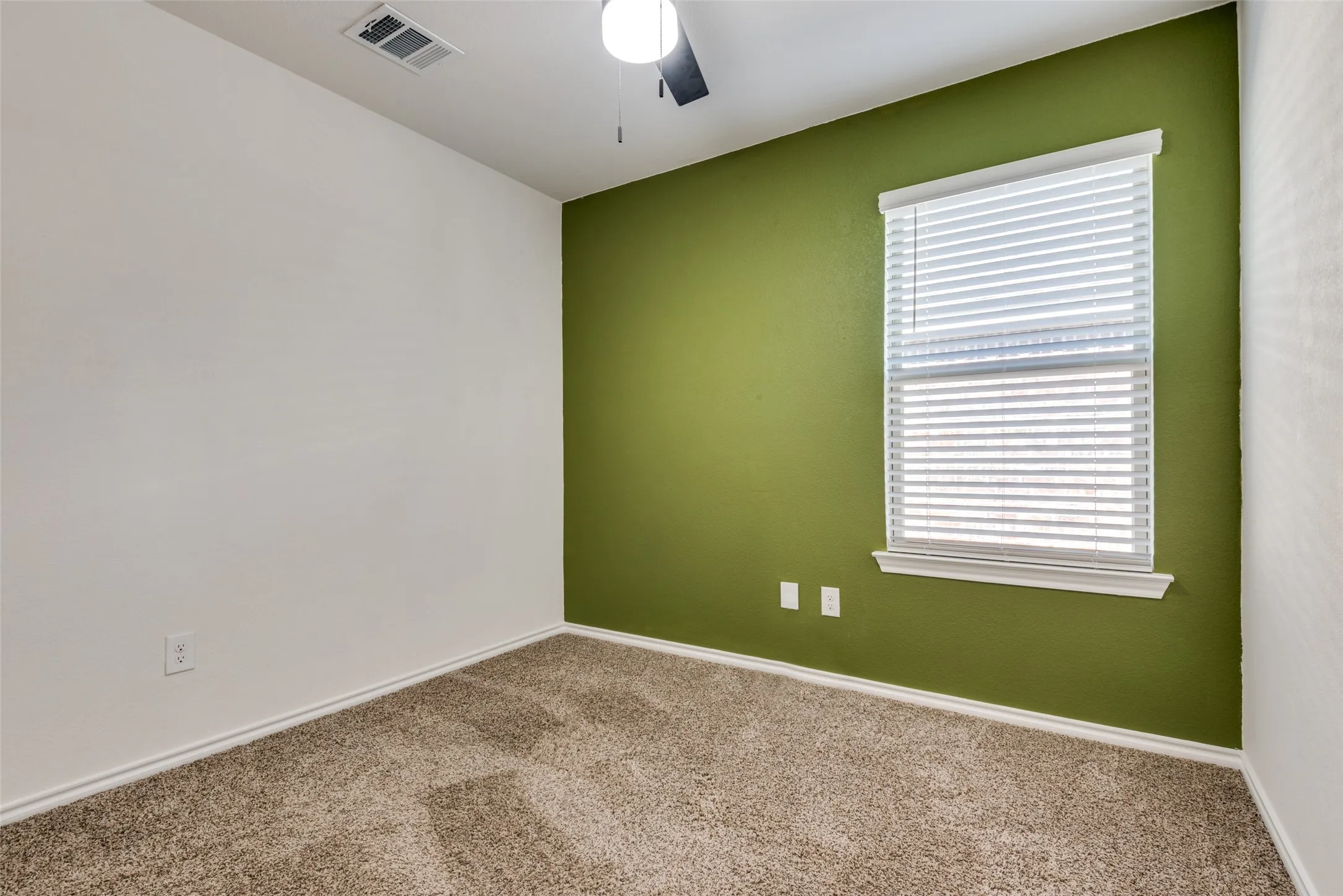 Carpeted flooring, single window with blinds, ceiling fan, and a painted accent wall