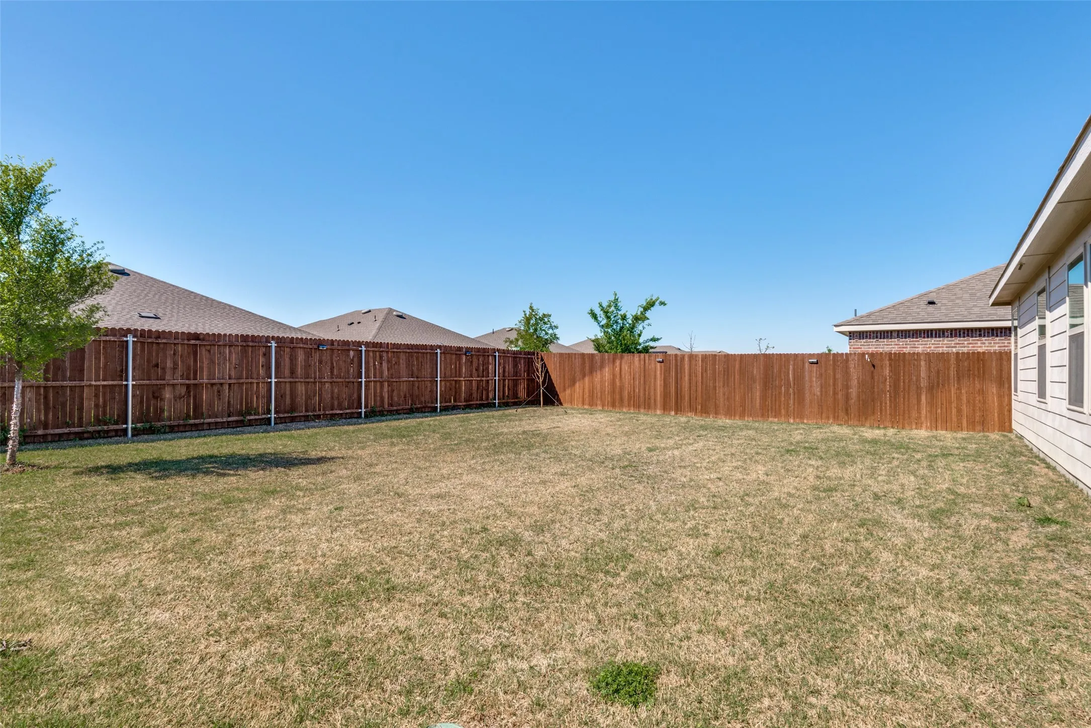 Expansive backyard featuring a wood privacy fence and a building exterior with horizontal siding