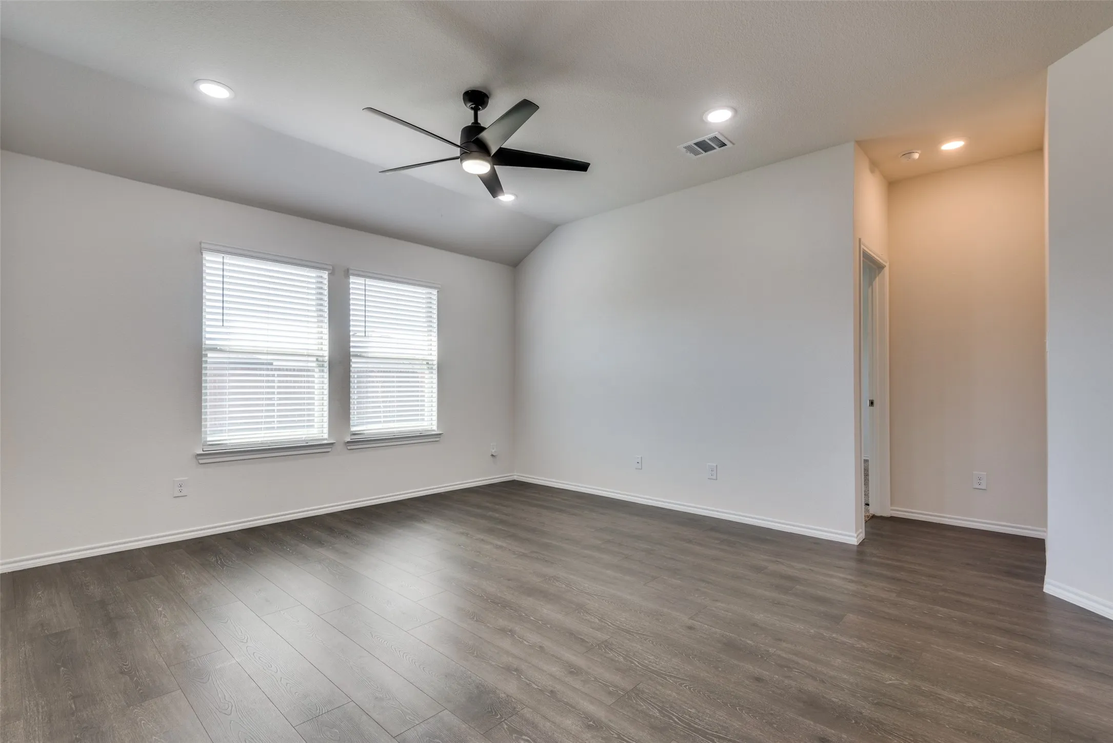 Vaulted ceiling, recessed lighting, ceiling fan, dual windows with blinds, wood-finish flooring