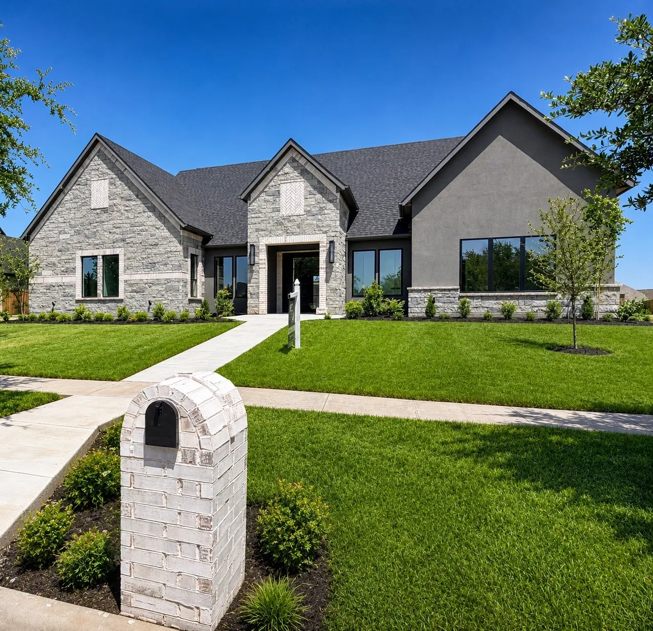 Stone and stucco exterior with dark-framed windows, a gabled roof, and a paved walkway