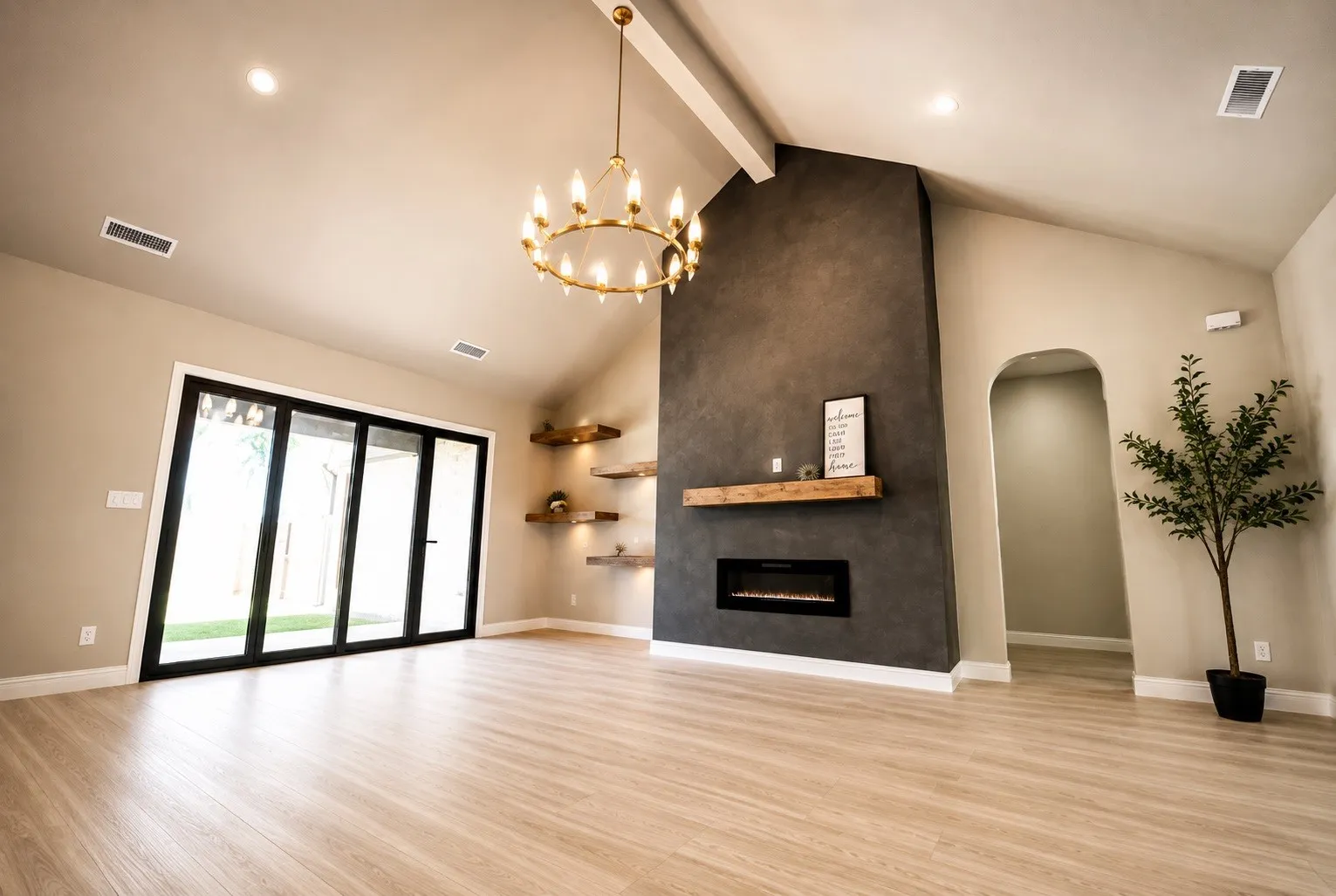 Vaulted ceiling with exposed beam, wood-finish flooring, linear electric fireplace with wood mantel, built-in shelving, and bifold glass doors