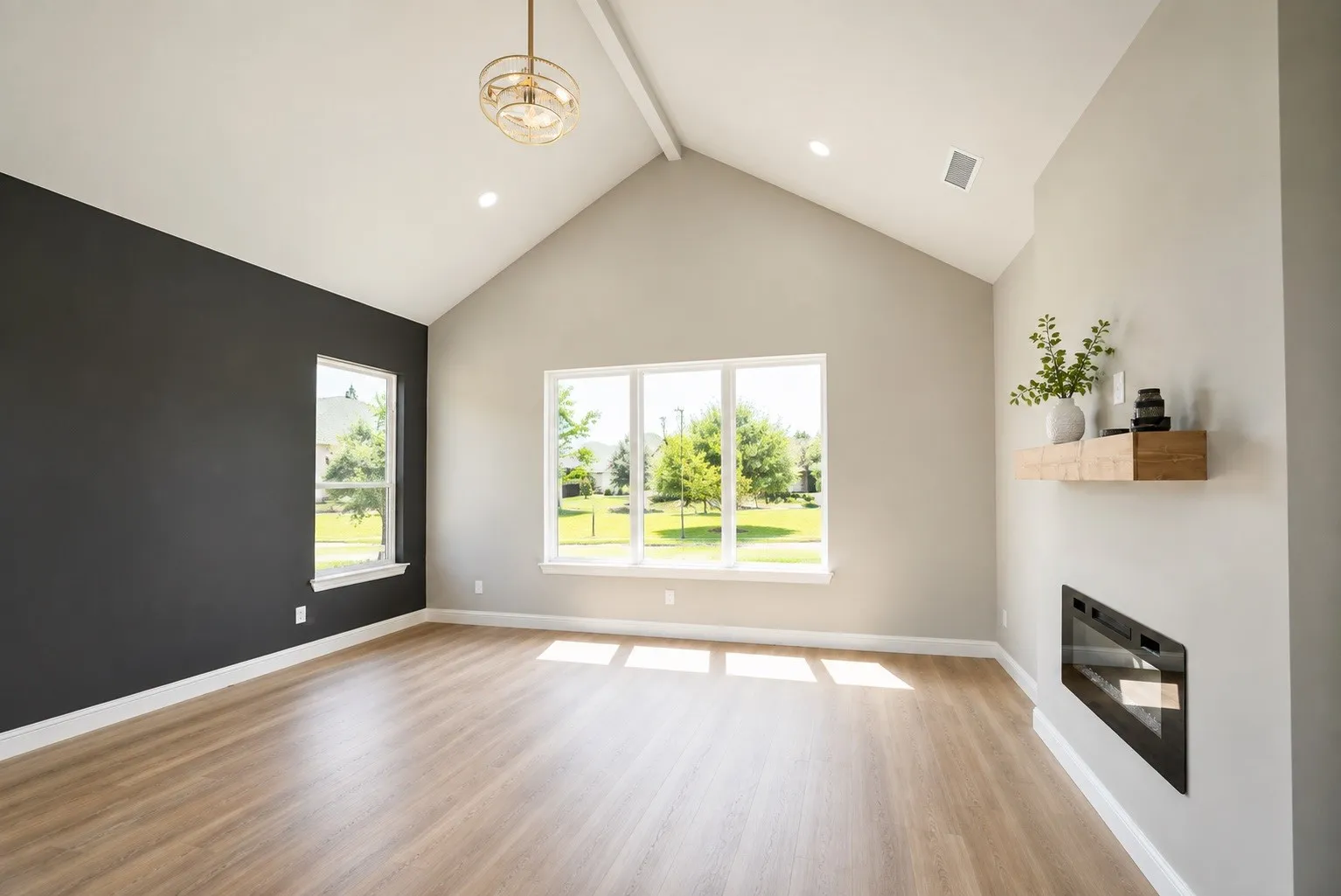 Vaulted ceiling with an exposed beam, wood-finish flooring, multiple windows, a wall-mounted electric fireplace, and a wood mantel