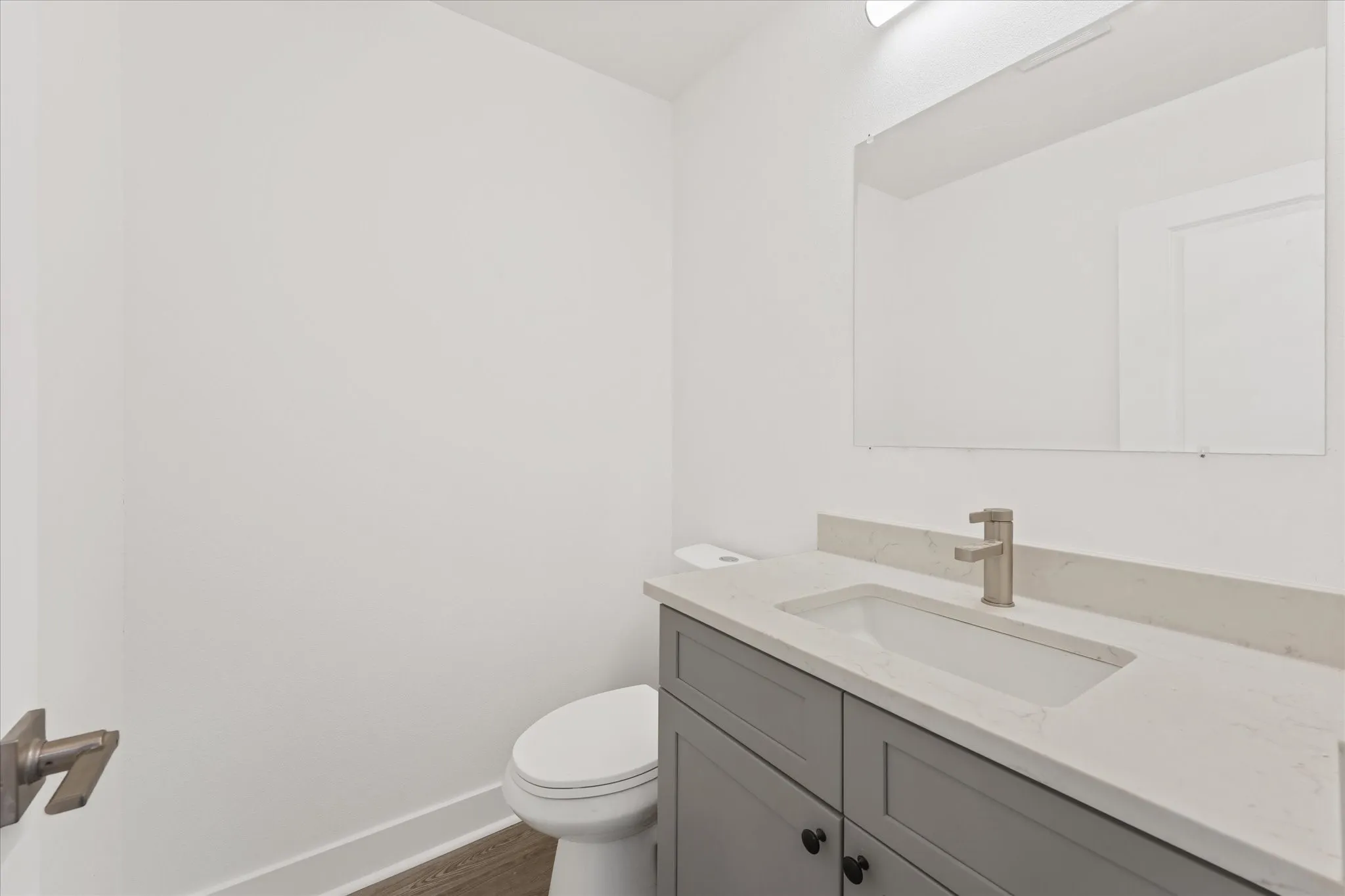 Vanity with gray cabinetry, white countertop, under-mount sink, and brushed nickel faucet