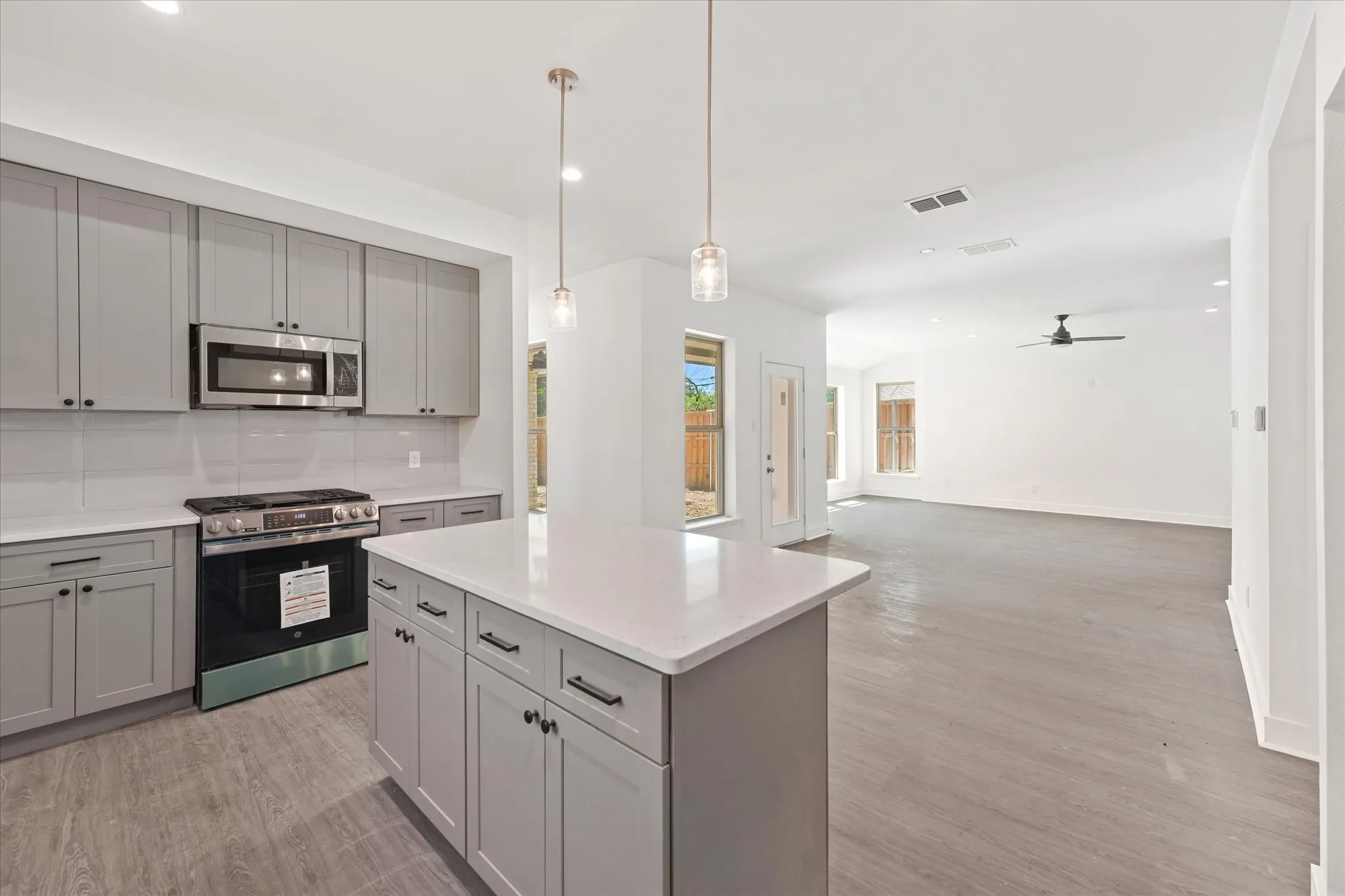 Open-concept kitchen with a central island, stainless steel appliances, and sleek gray cabinetry