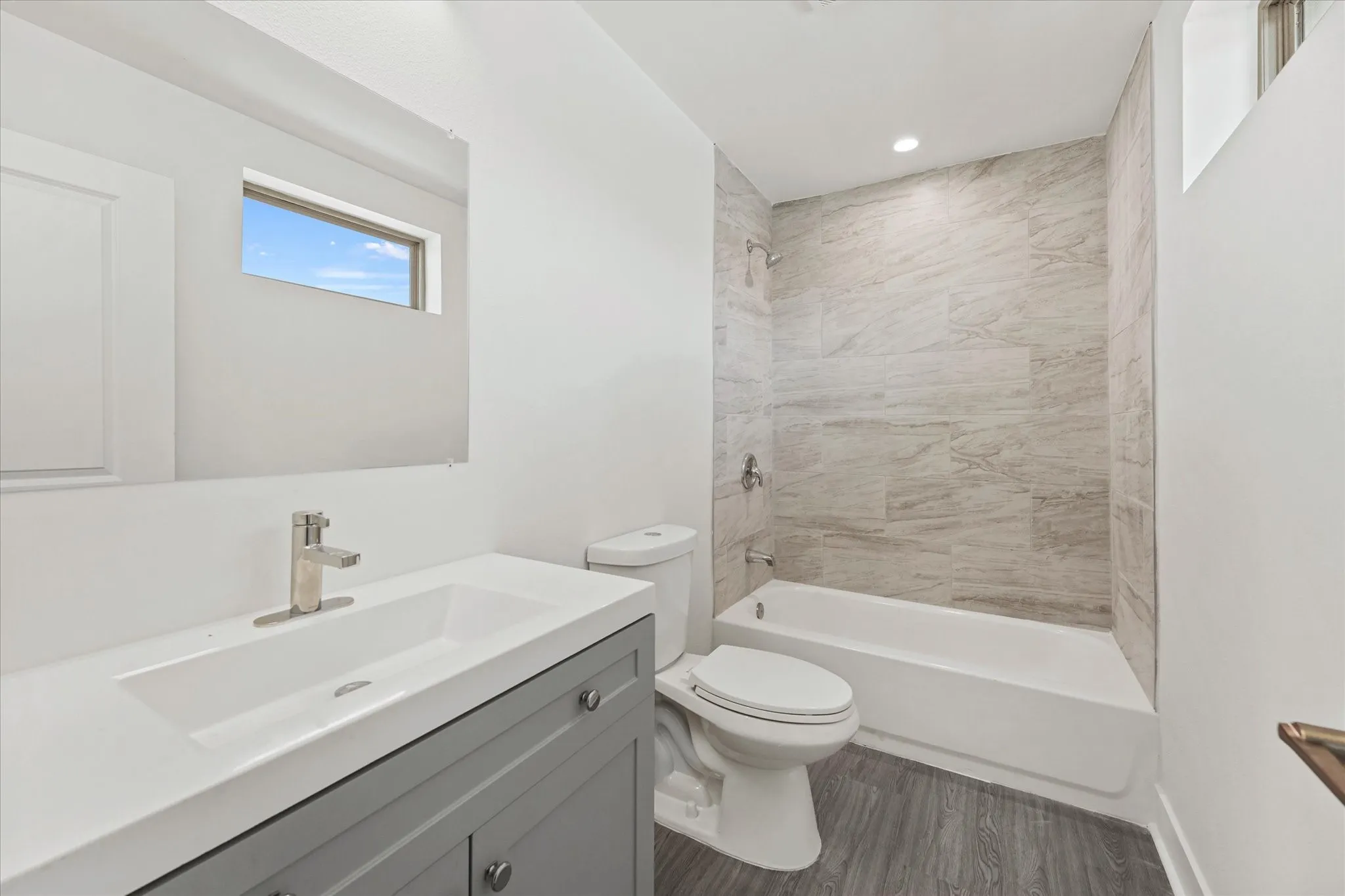 White vanity with a single basin sink, brushed nickel faucet, and gray cabinetry