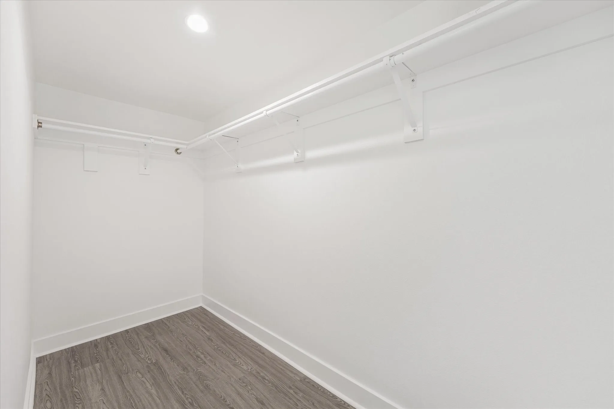 Recessed ceiling light, shelving system, clothing rods, wood-finish flooring, white walls