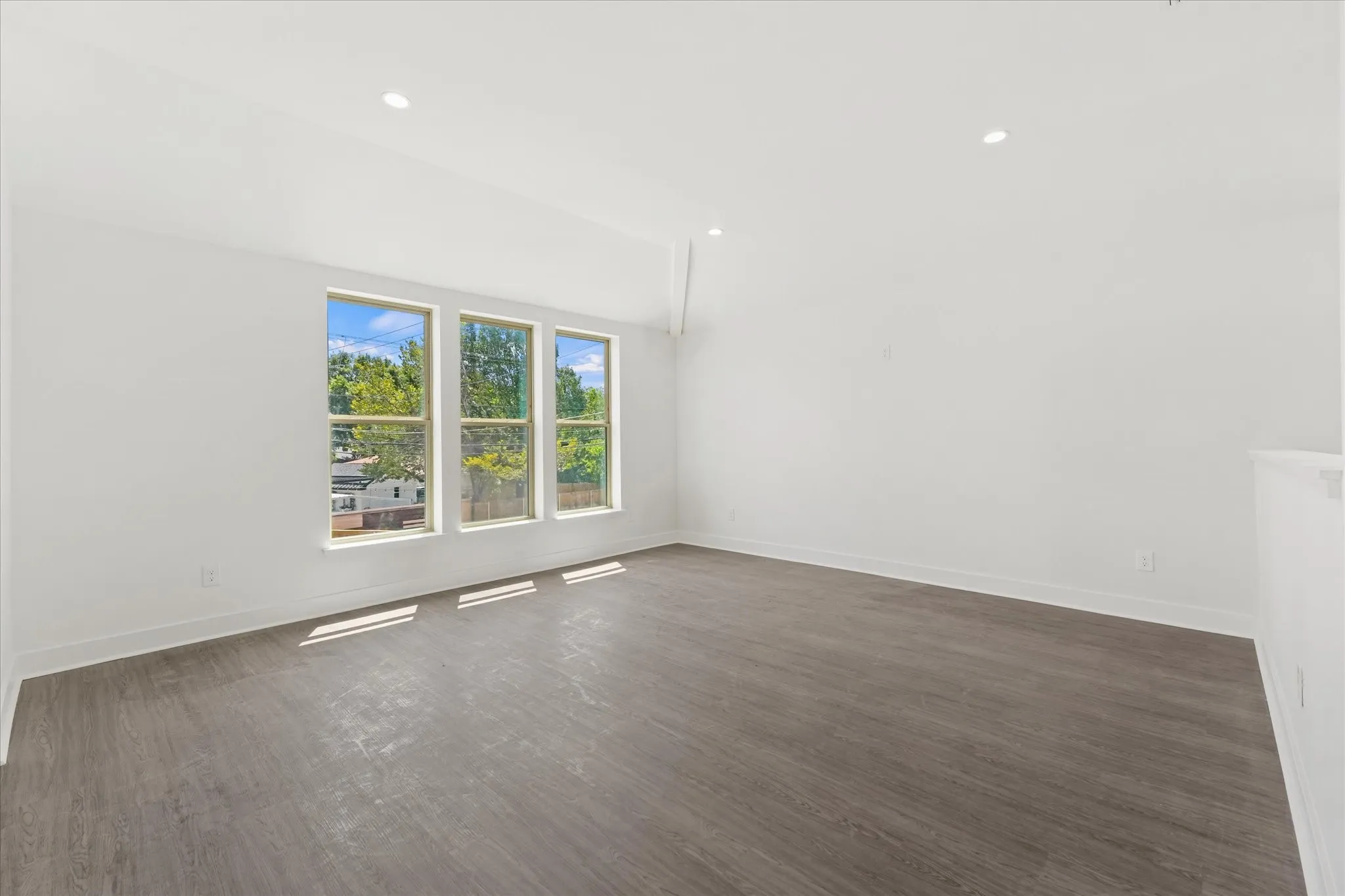 Wood-finish flooring, recessed lighting, and three tall windows
