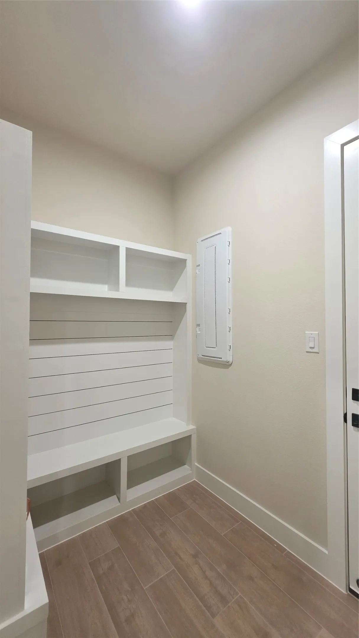 Built-in hall tree with open shelving and bench seating, wood-finish flooring, and recessed ceiling lighting