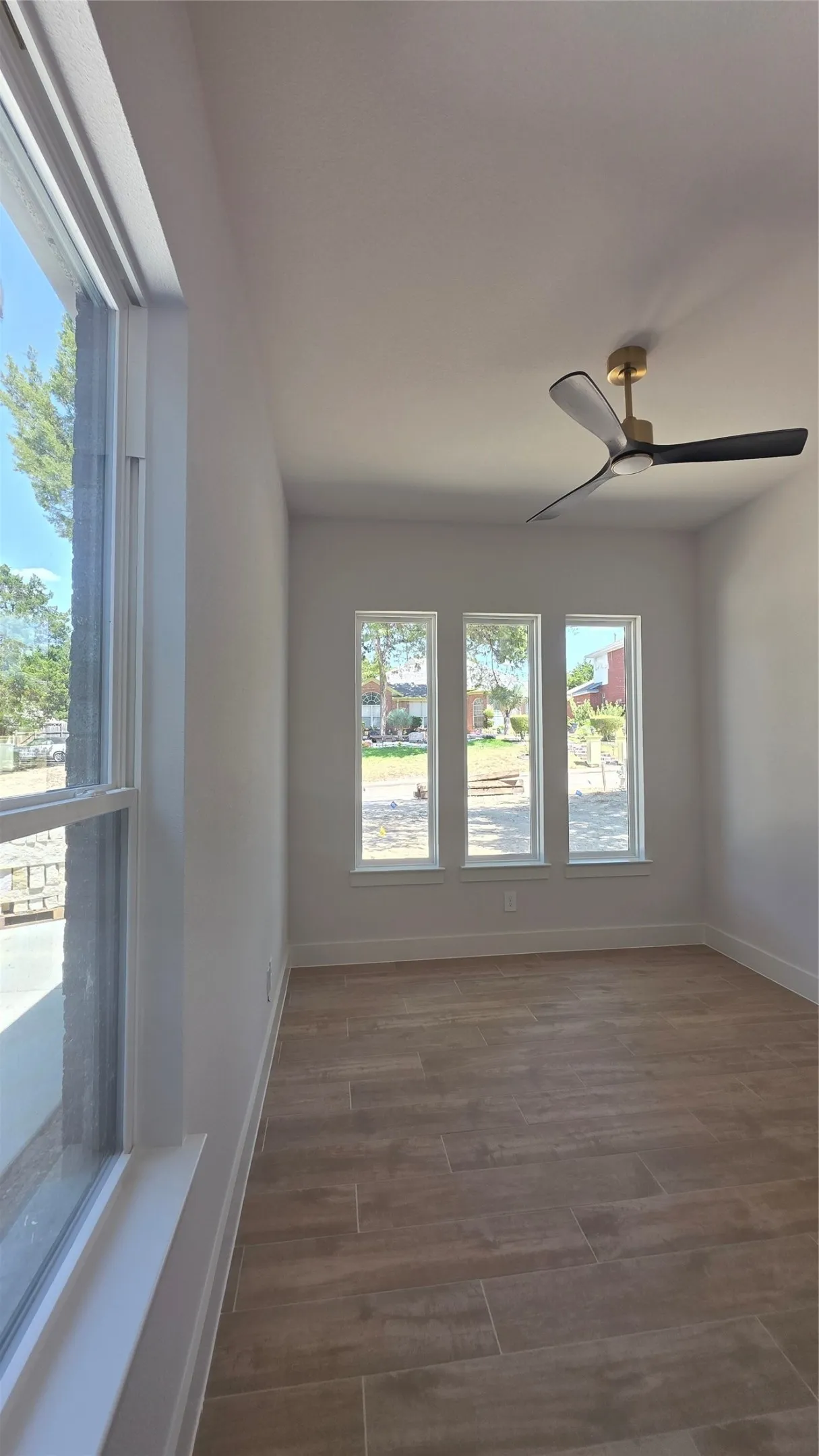 Recessed lighting, contemporary ceiling fan, wood-finish flooring, multiple windows, and white trim throughout