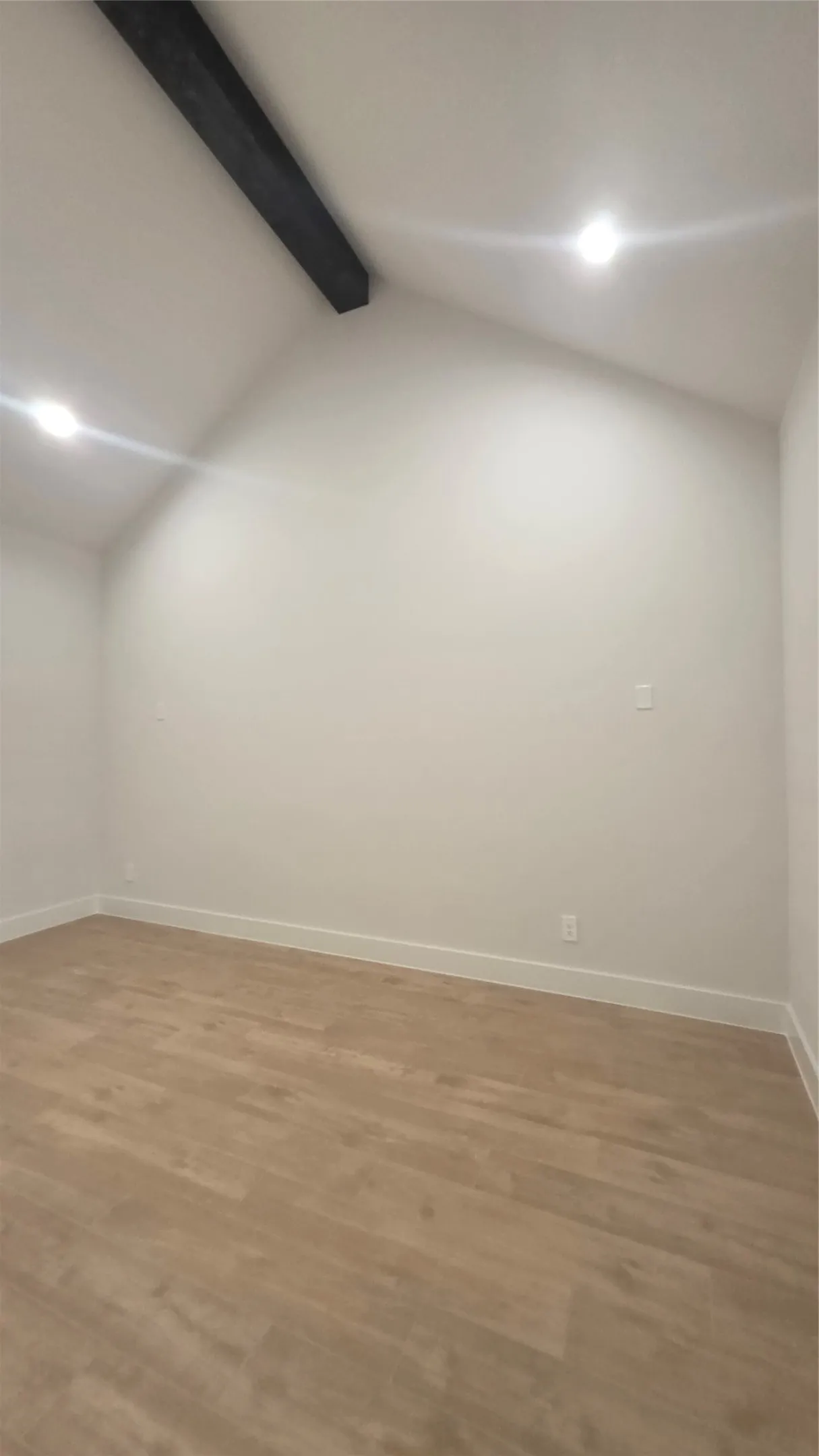 Vaulted ceiling with exposed beam, recessed lighting, and wood-finish flooring