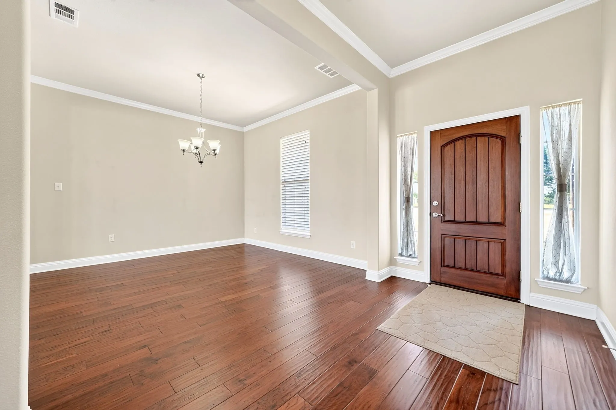 Rich wood-finish flooring complemented by a substantial wood entry door with vertical panels