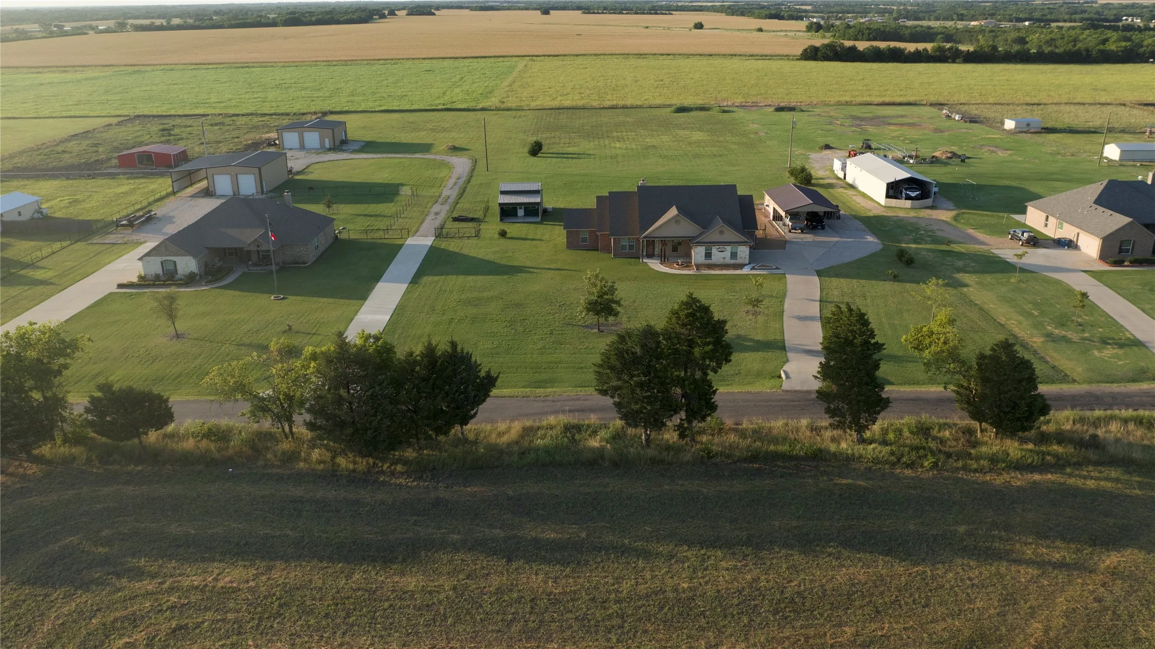 Expansive property featuring a central residence, multiple accessory structures, concrete driveways, and manicured lawns