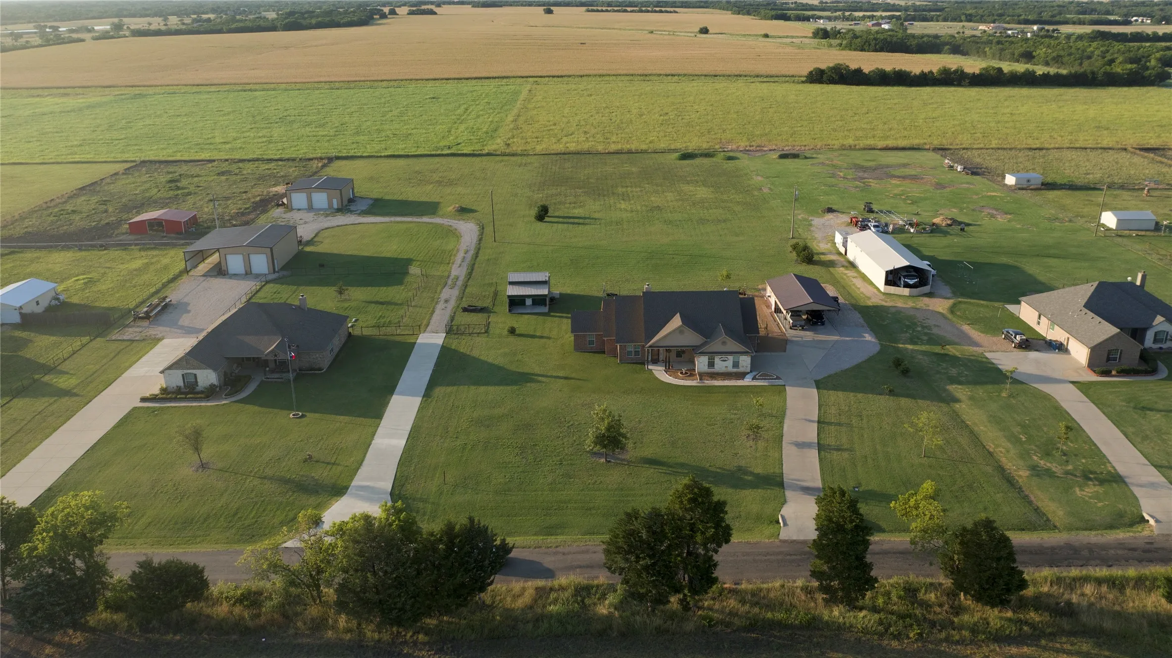 Expansive property featuring a residence with a covered front porch, a separate multi-bay garage structure, and a large covered open-sided structure