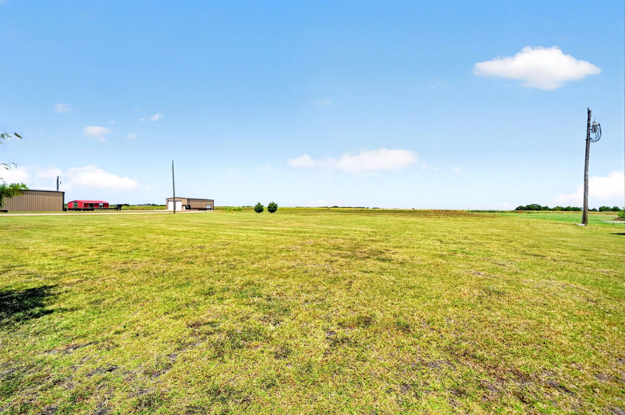 Expansive grassy terrain with distant structures and open skies.
