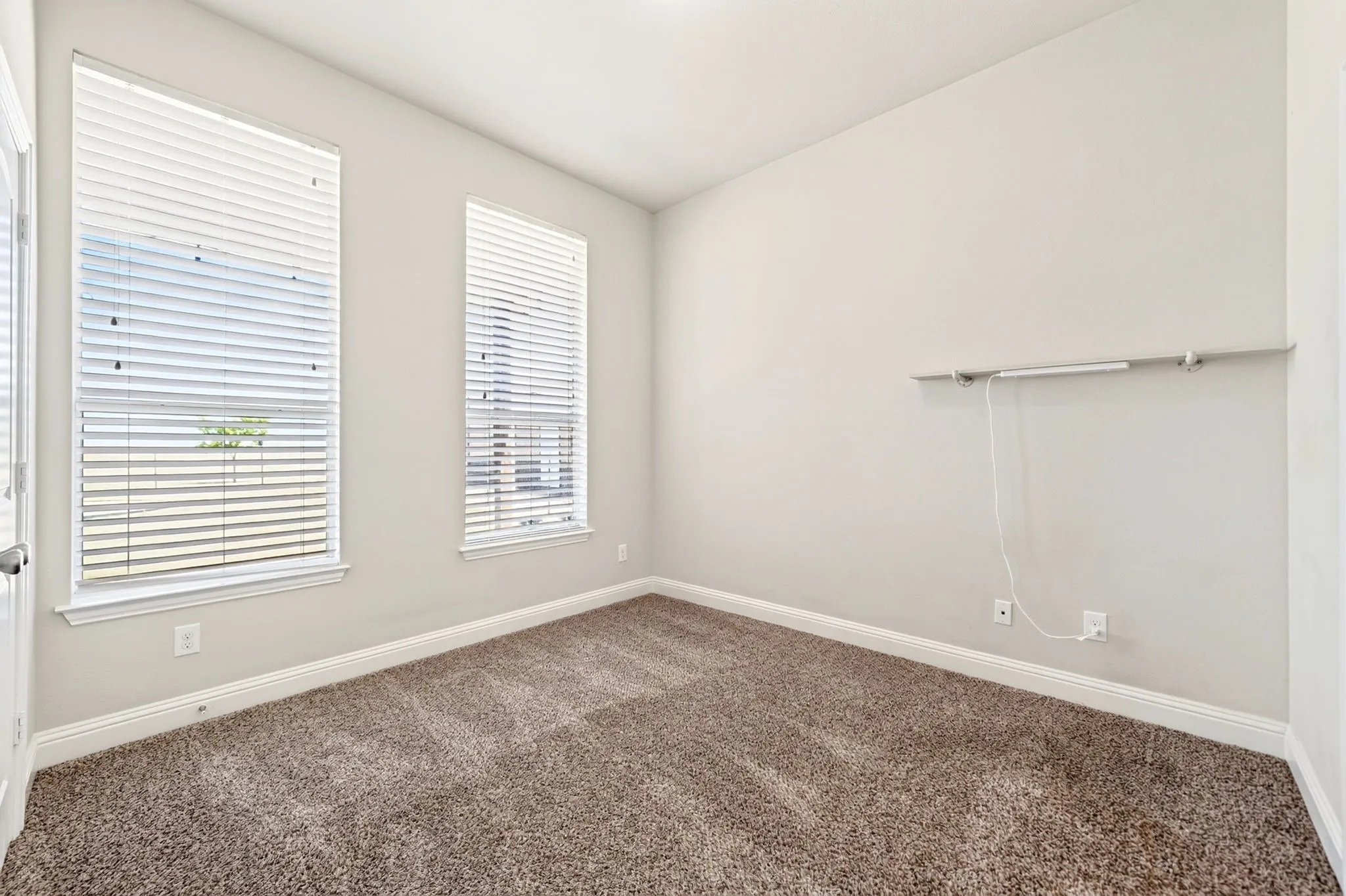 Neutral wall paint, two windows with blinds, and carpeted flooring with ensuite full bathroom