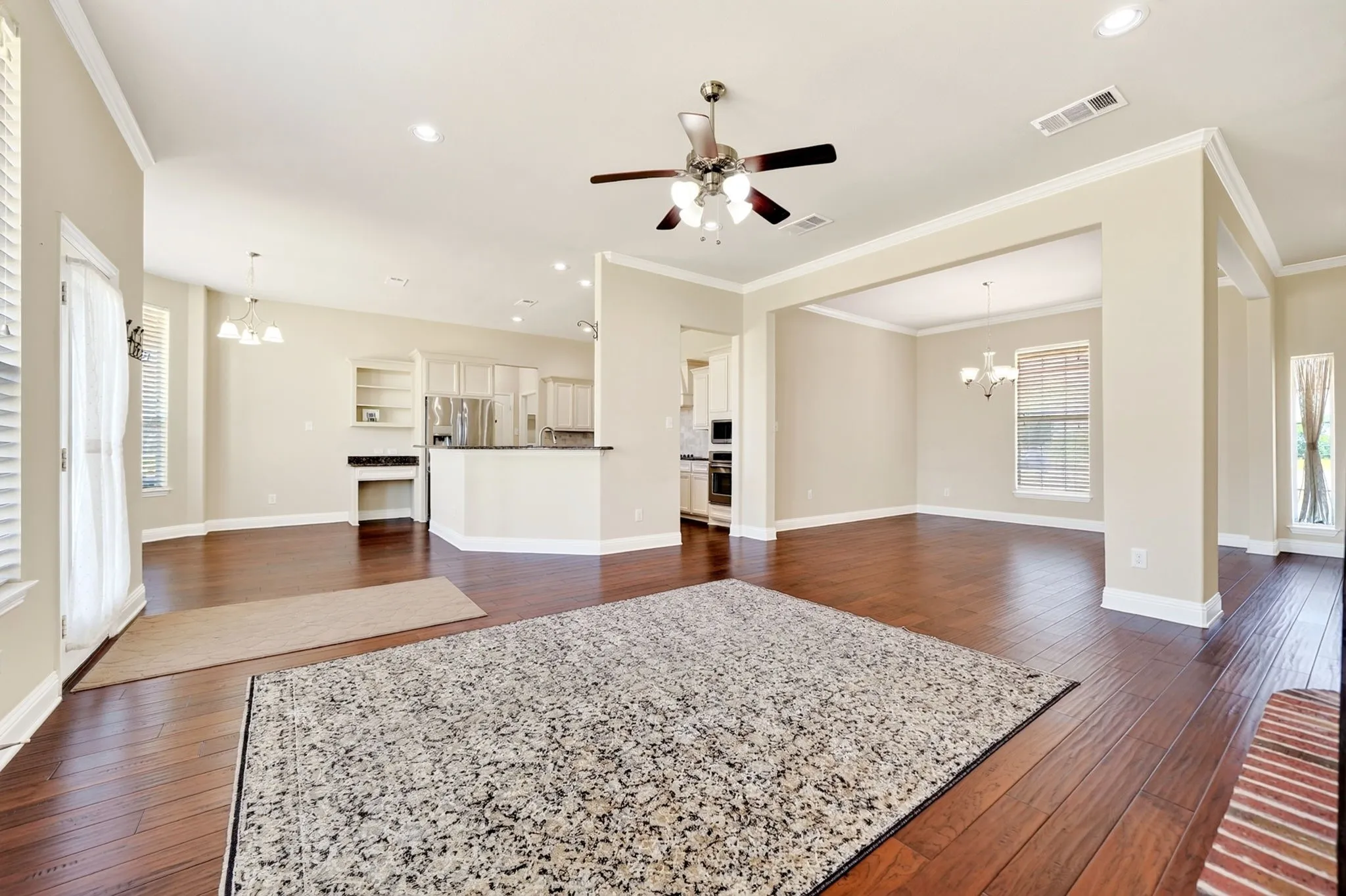 Rich wood-finish flooring throughout, featuring a kitchen with a built-in desk area and stainless steel appliances