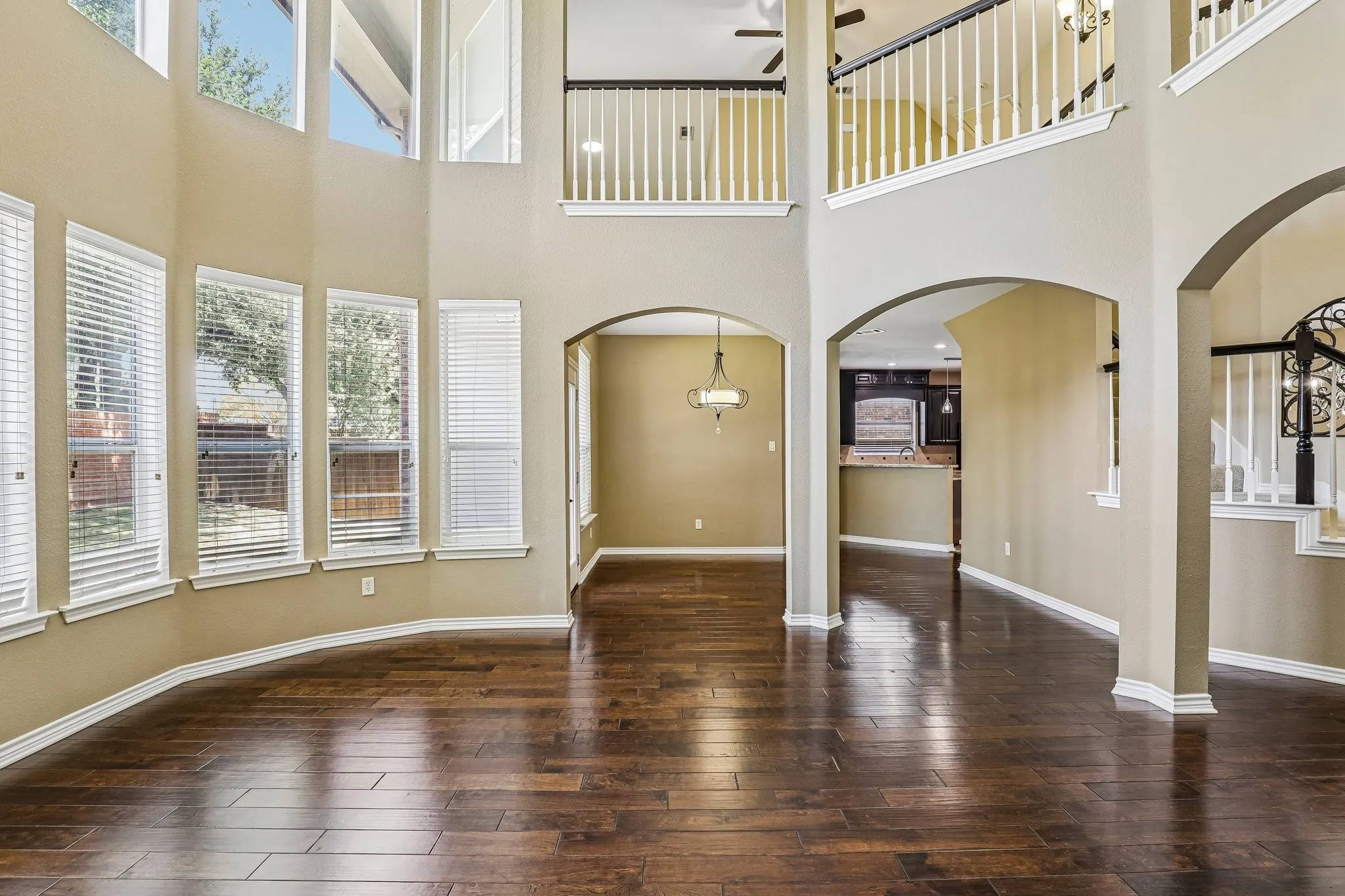 Living room features wall of stacked windows with natural light and balconies from second story.