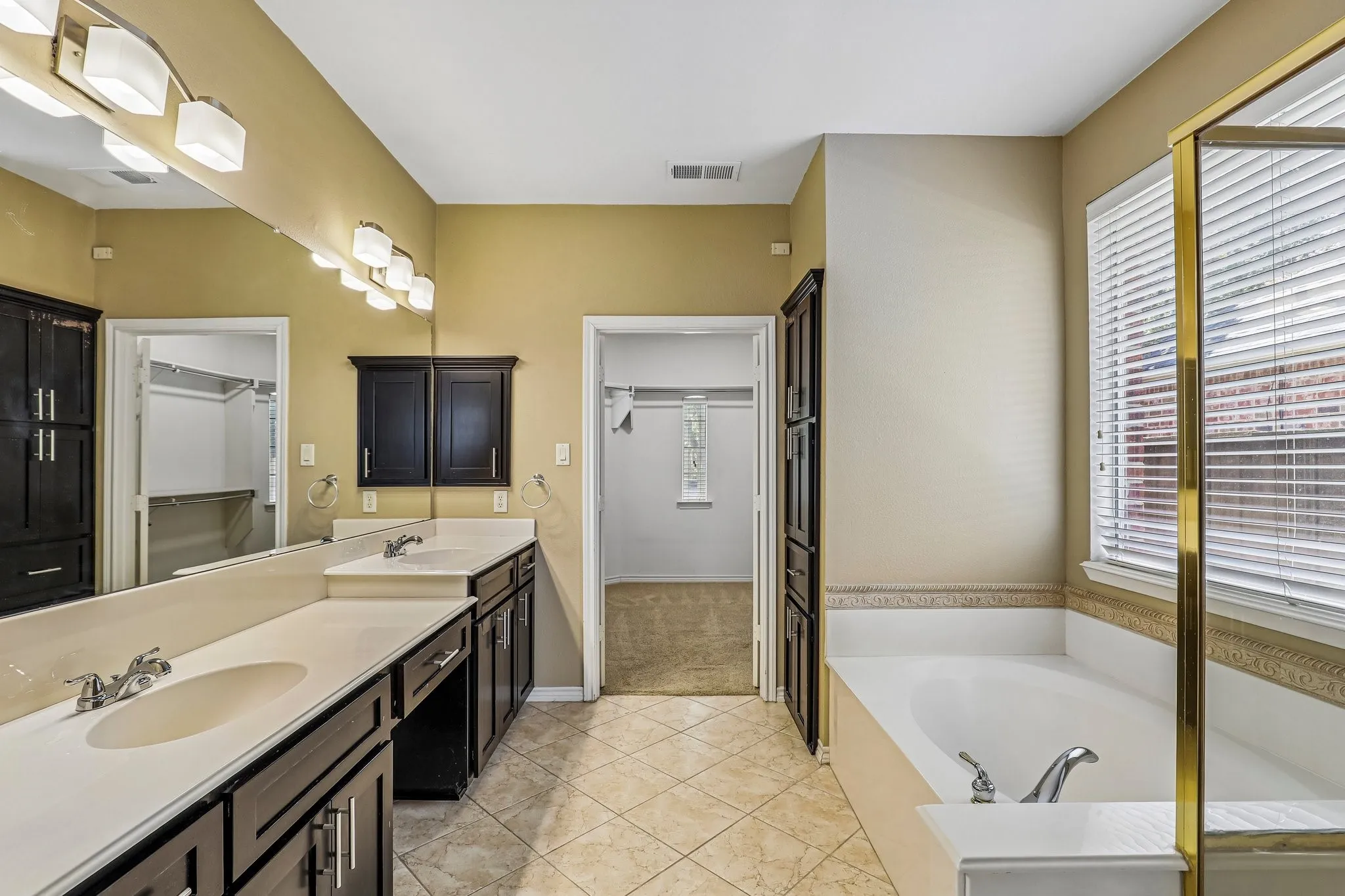 En-suite bath with dual sinks and vanity sitting area.