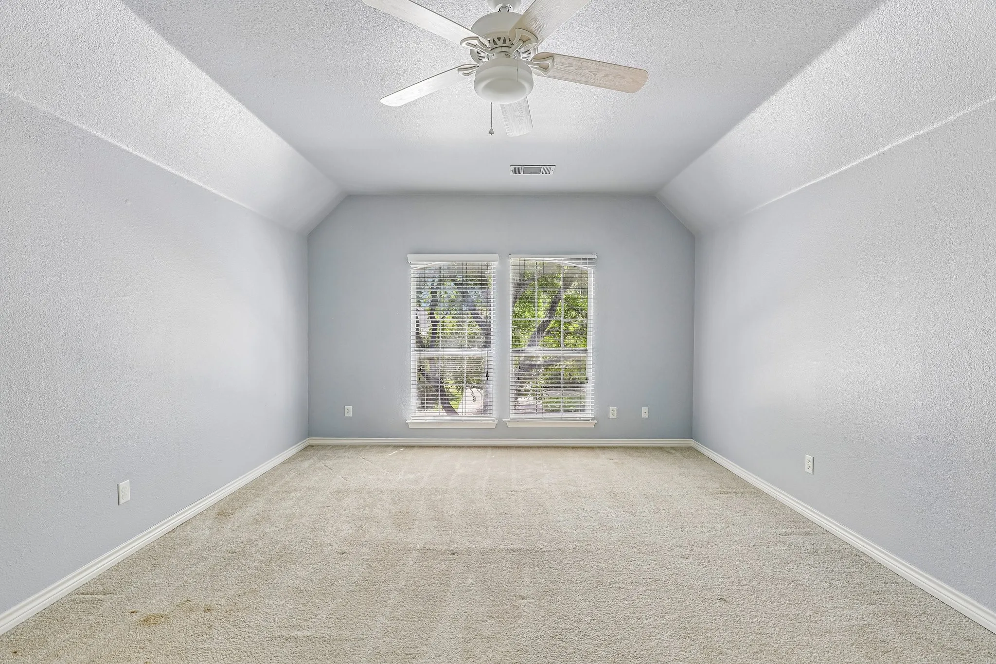 Upstairs game room with sloped ceiling and natural light.