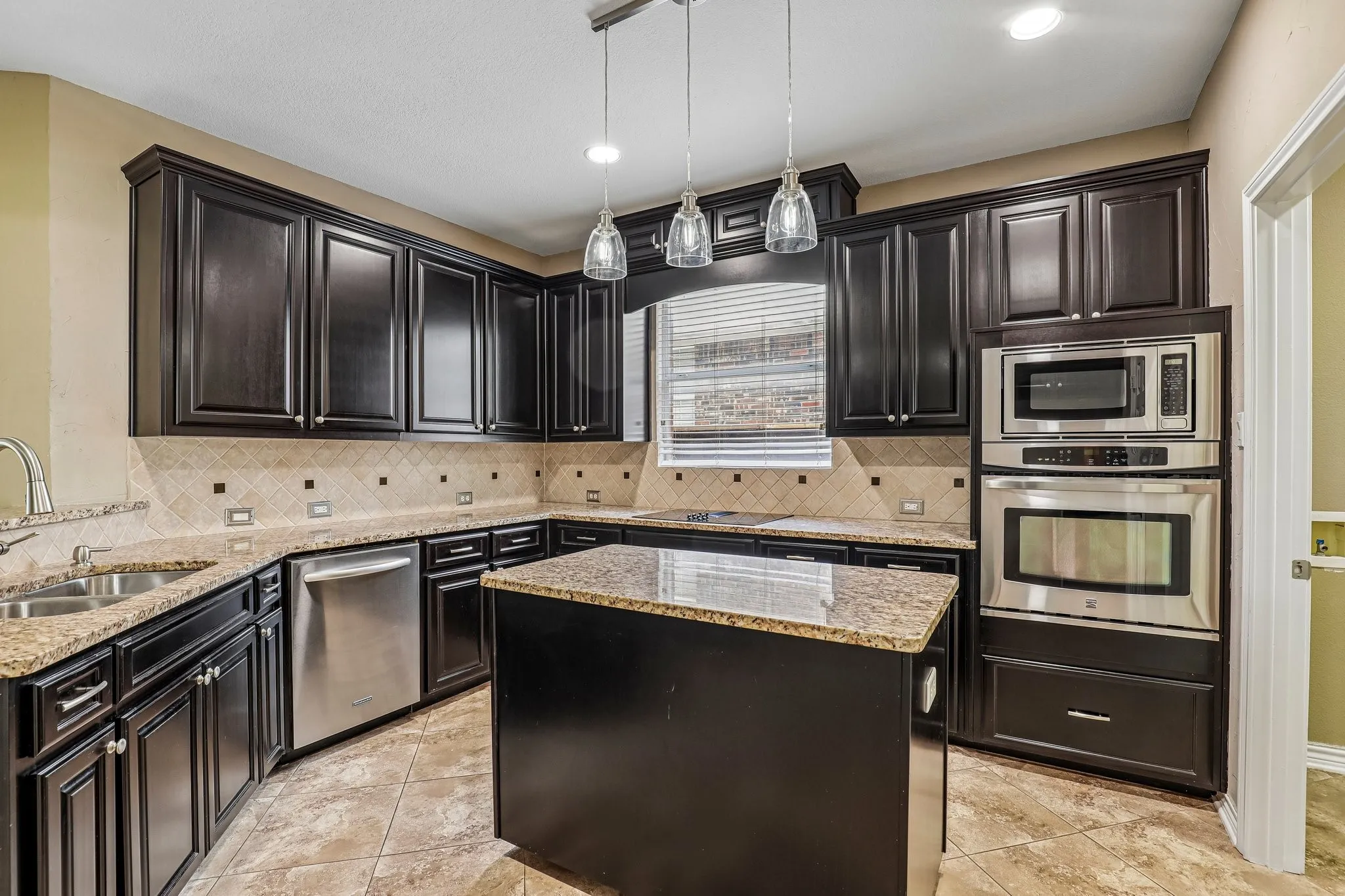 Kitchen features rich wood cabinetry and prep island.