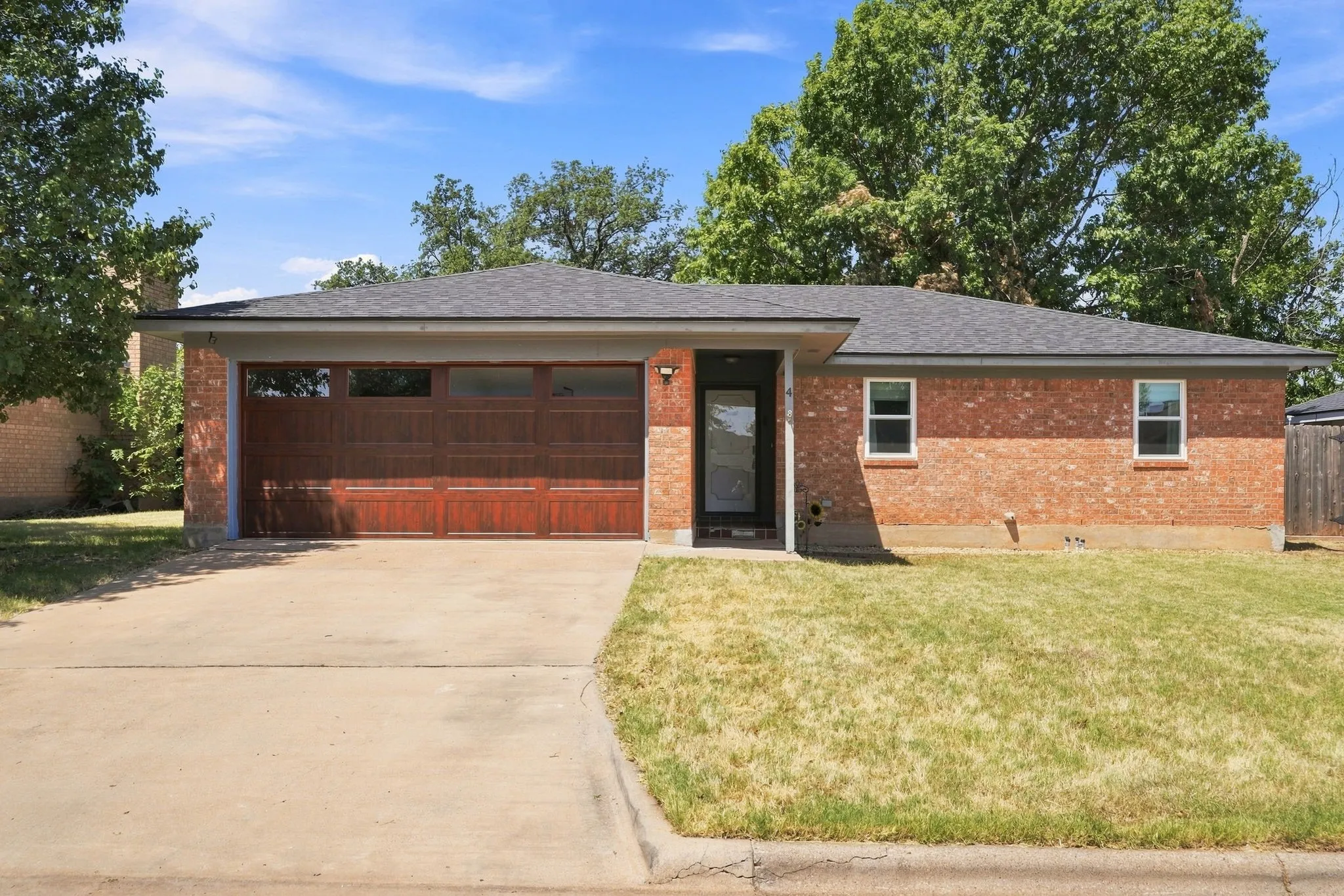 Brick exterior with a dark shingle roof, integrated garage, and concrete driveway