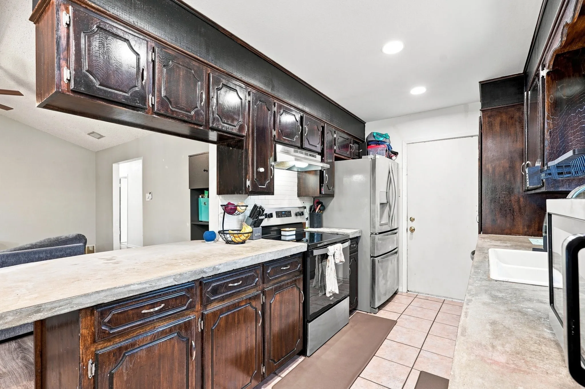 Kitchen featuring wood cabinetry, light-toned countertops, and tile flooring