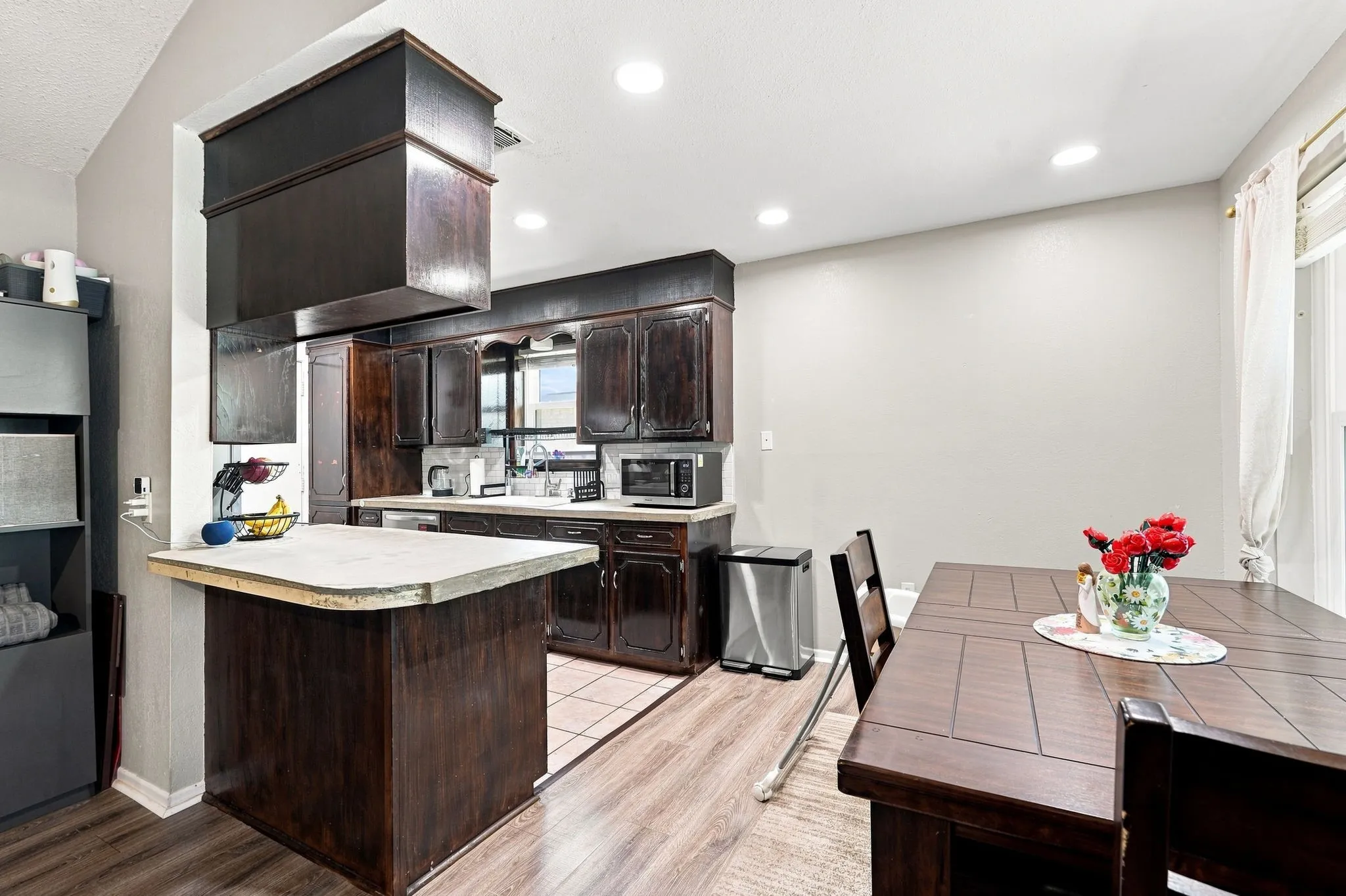 Kitchen featuring dark wood-finish cabinetry, a peninsula with a light-toned countertop, and recessed lighting