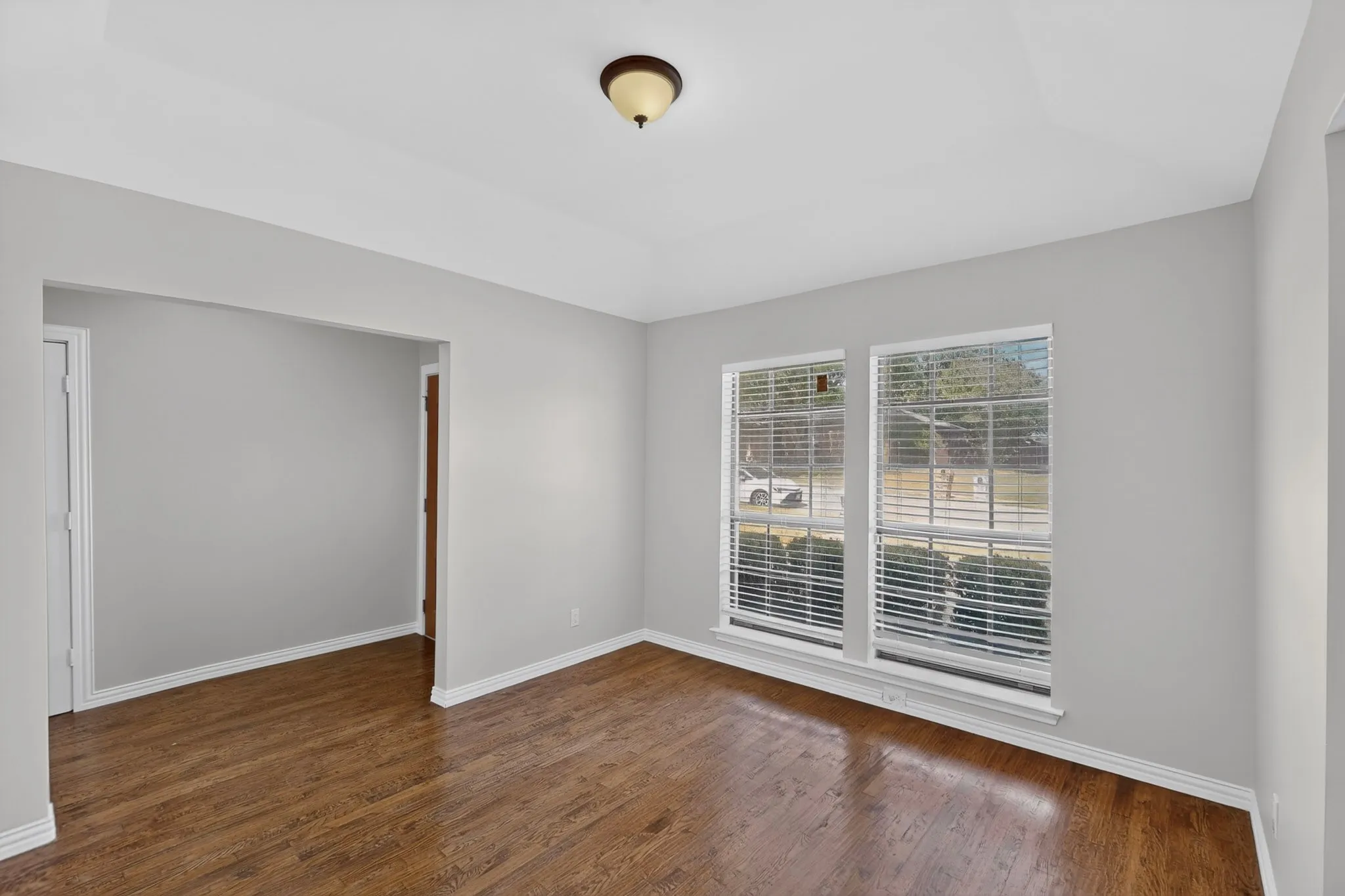 Wood-finish flooring, light grey wall paint, and multiple windows with blinds