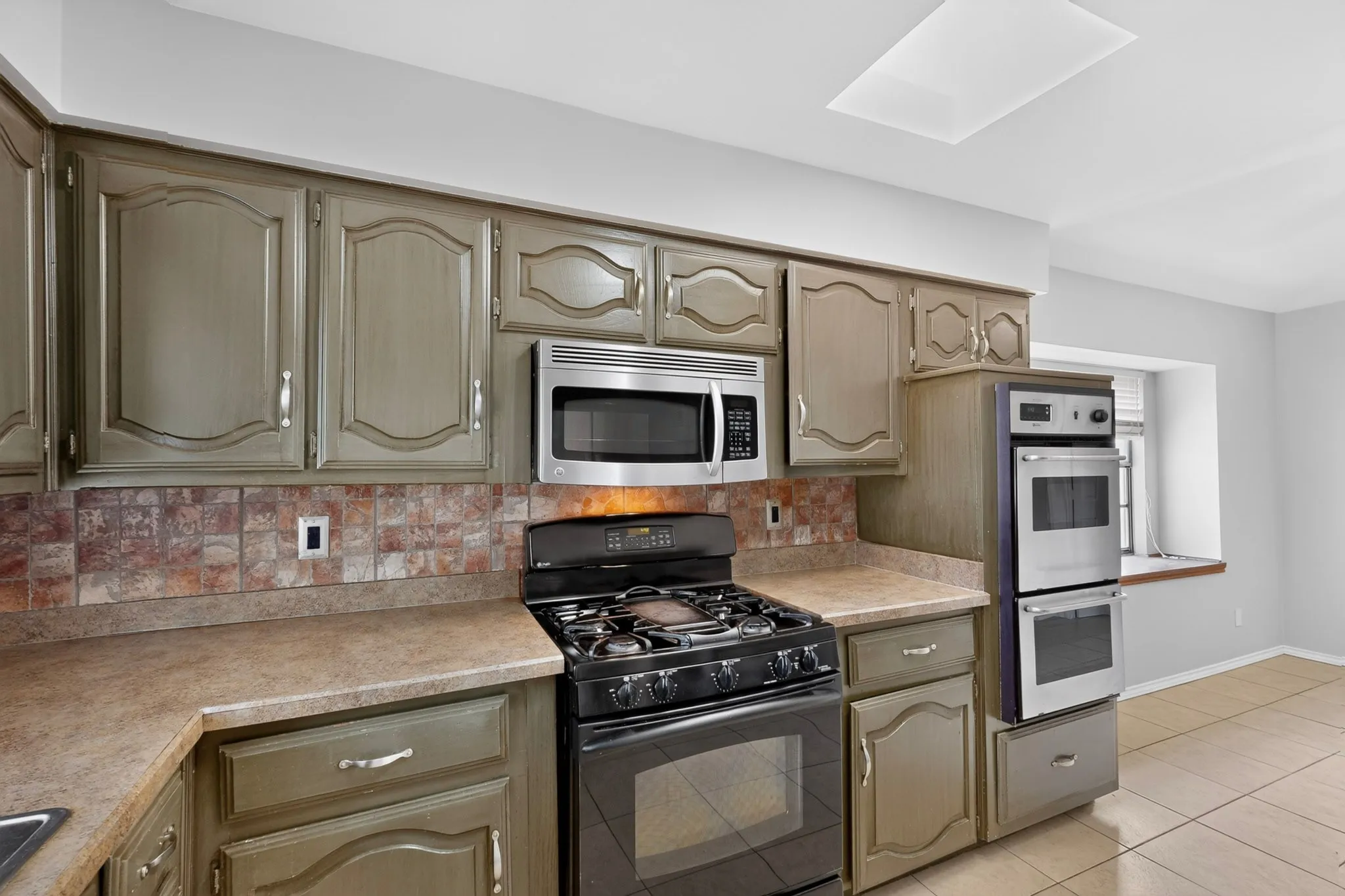 Kitchen featuring full-height cabinetry, tile backsplash, built-in stainless steel appliances, and a gas range