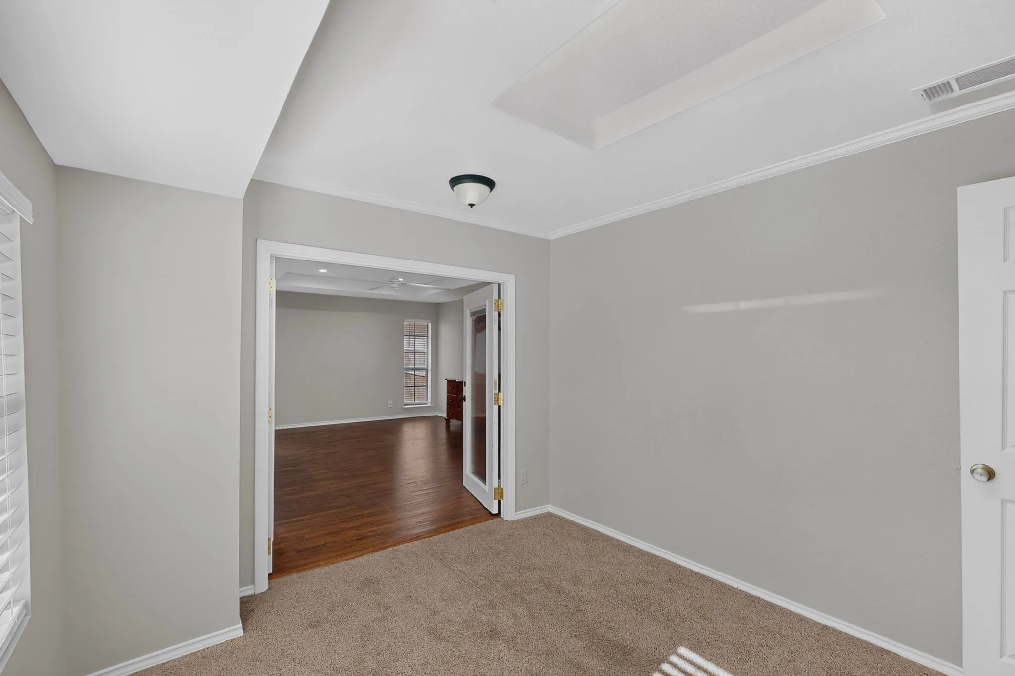 Recessed ceiling detail, light gray wall paint, white trim, carpet flooring, and a ceiling-mounted light fixture