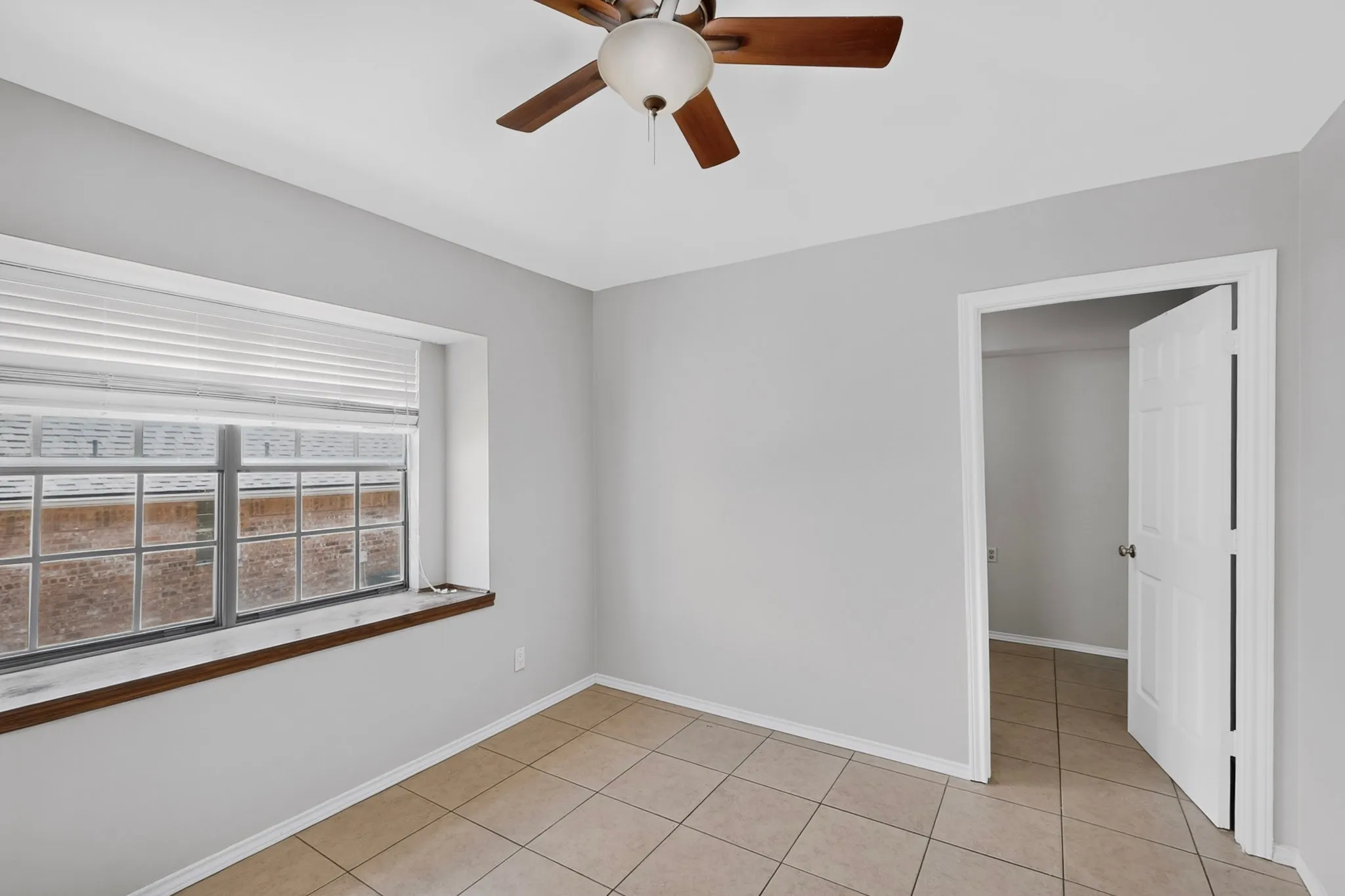 Neutral wall color, ceiling fan, window with horizontal blinds, tile flooring, and white trim