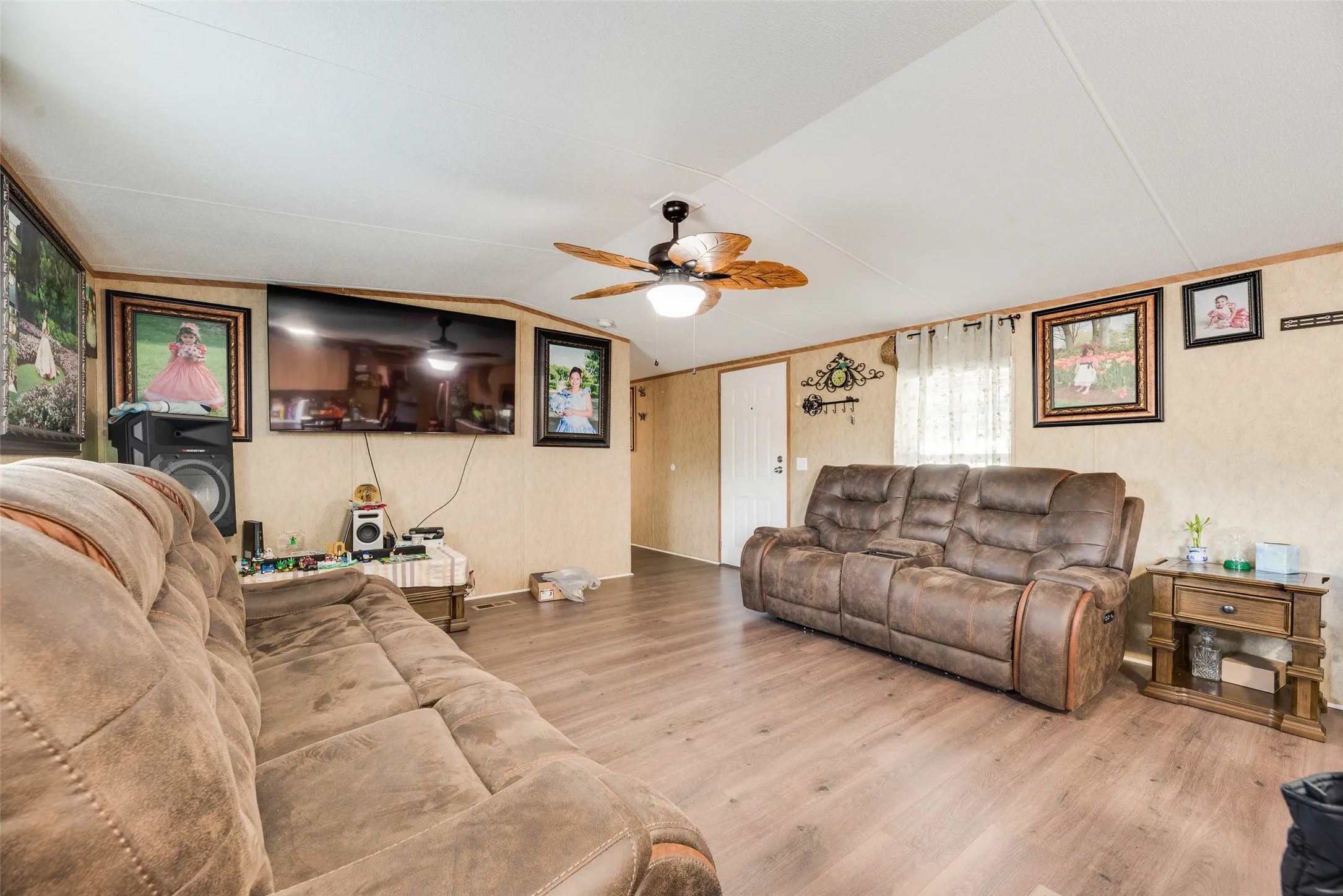 Wood-finish flooring, ceiling fan with light fixture, and a white interior door
