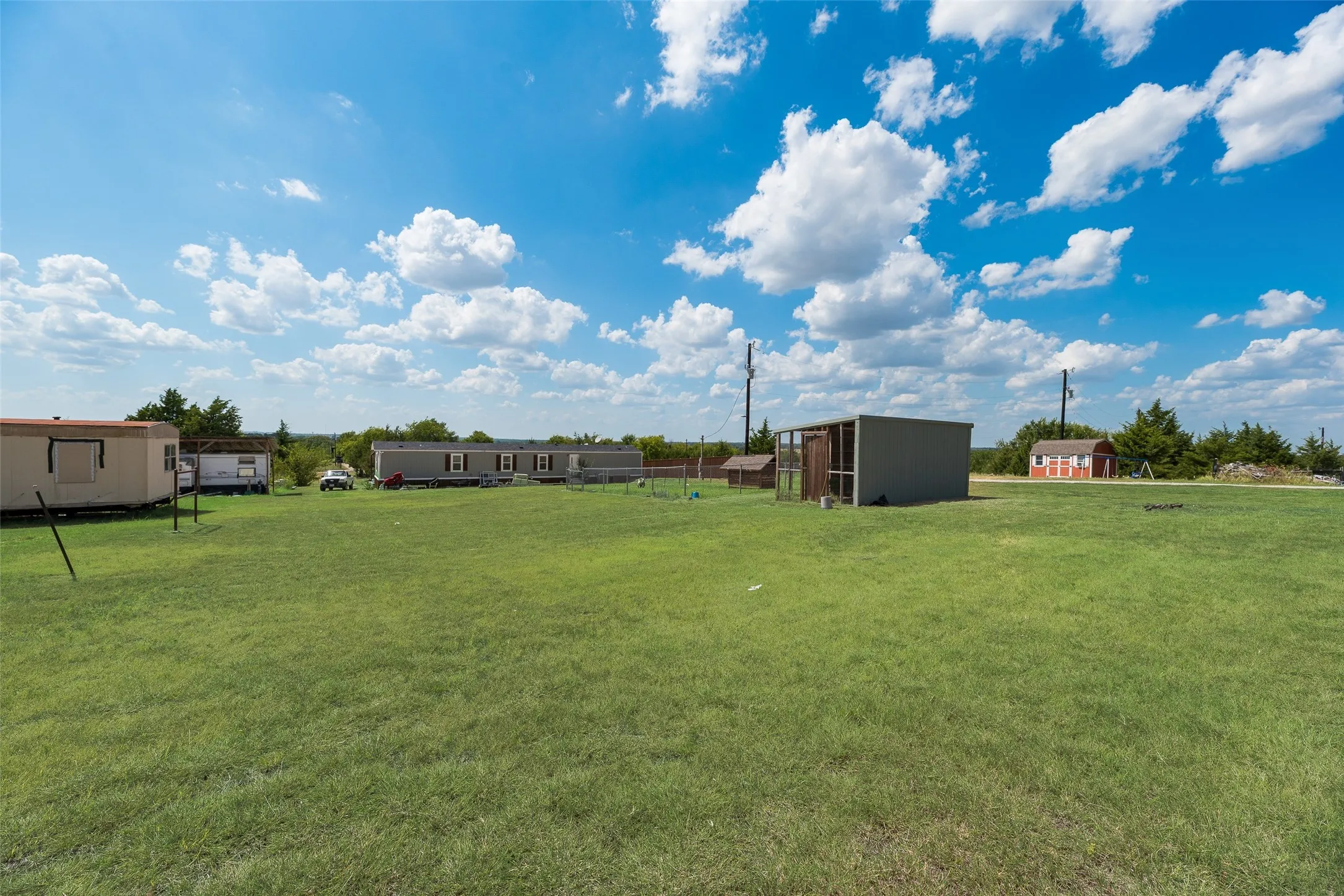 Expansive grassy terrain with multiple residential structures and outbuildings