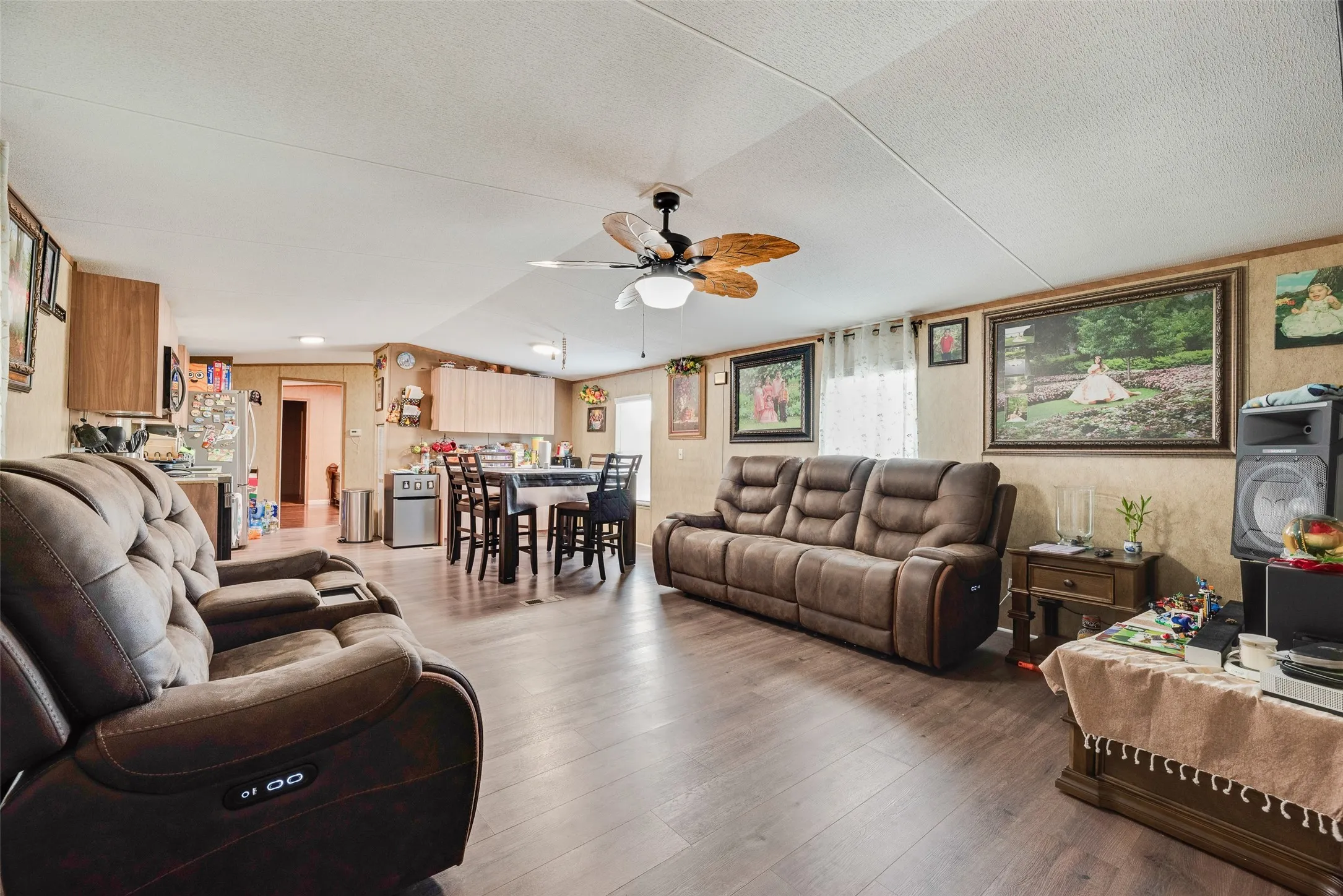 Open-concept living space featuring wood-finish flooring, a ceiling fan with integrated lighting, and a dining area with built-in cabinetry
