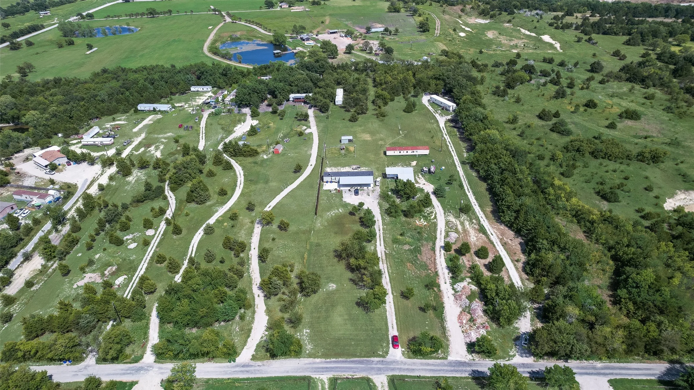 Expansive green landscape featuring multiple structures, numerous driveways, and scattered mature trees