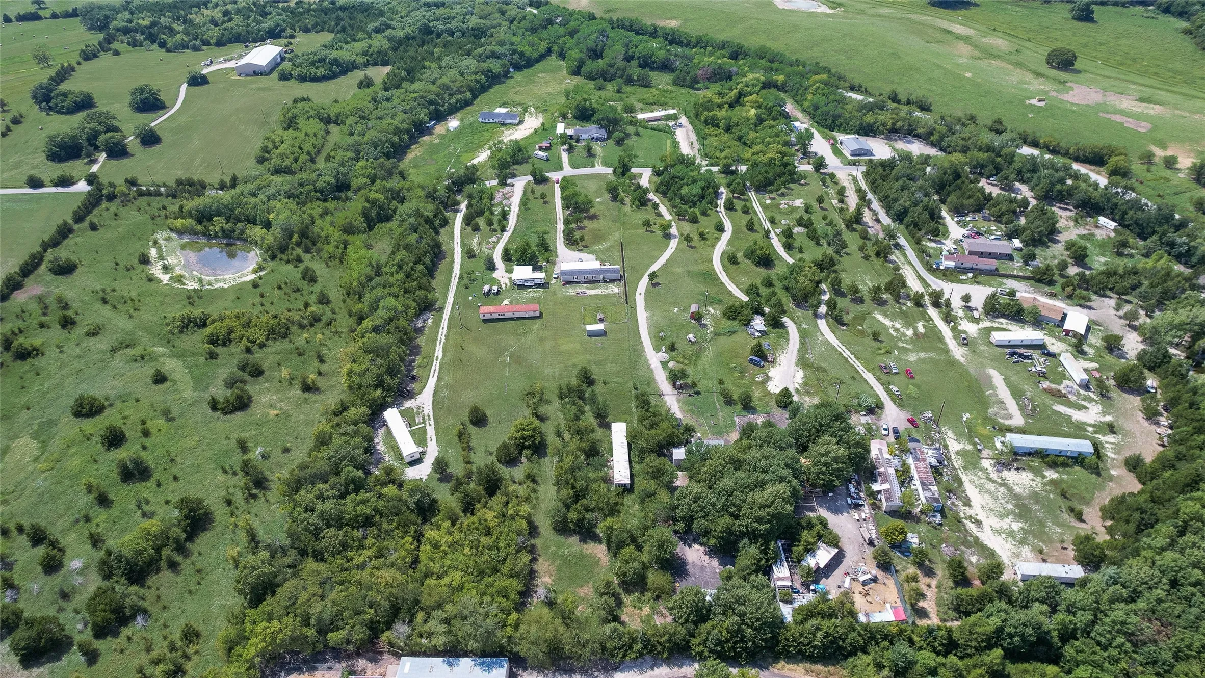 Expansive land parcel featuring multiple structures, extensive green space, and a pond