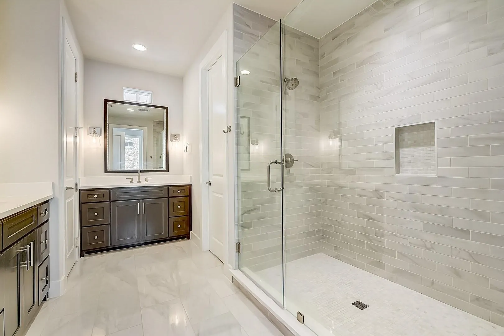 Expansive walk-in shower with a glass enclosure, horizontal tile surround, and built-in niche