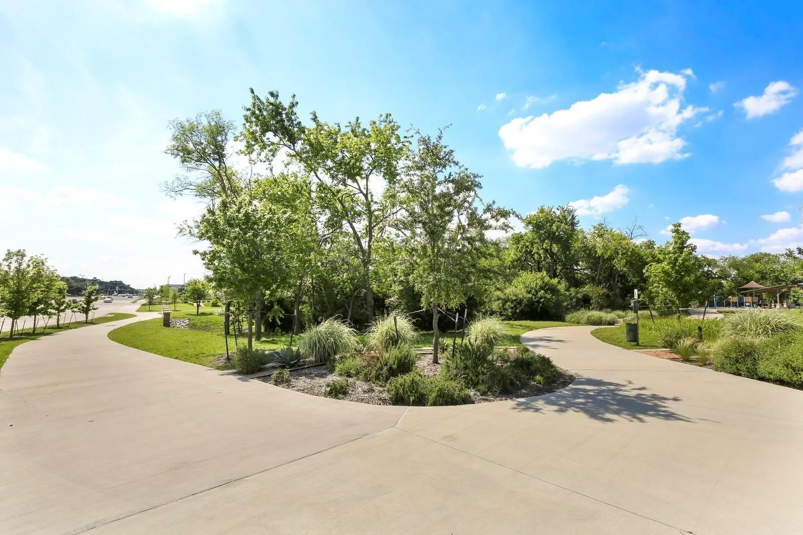 Paved pathways winding through green spaces with mature trees and maintained landscaping